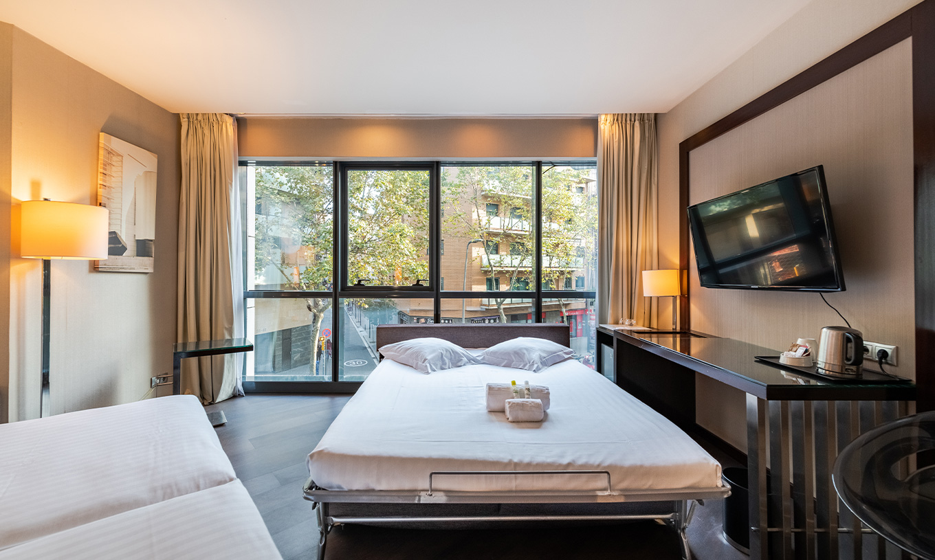Superior Family room at Pestana Arena Barcelona has a TV and a window with a view of the city of Barcelona