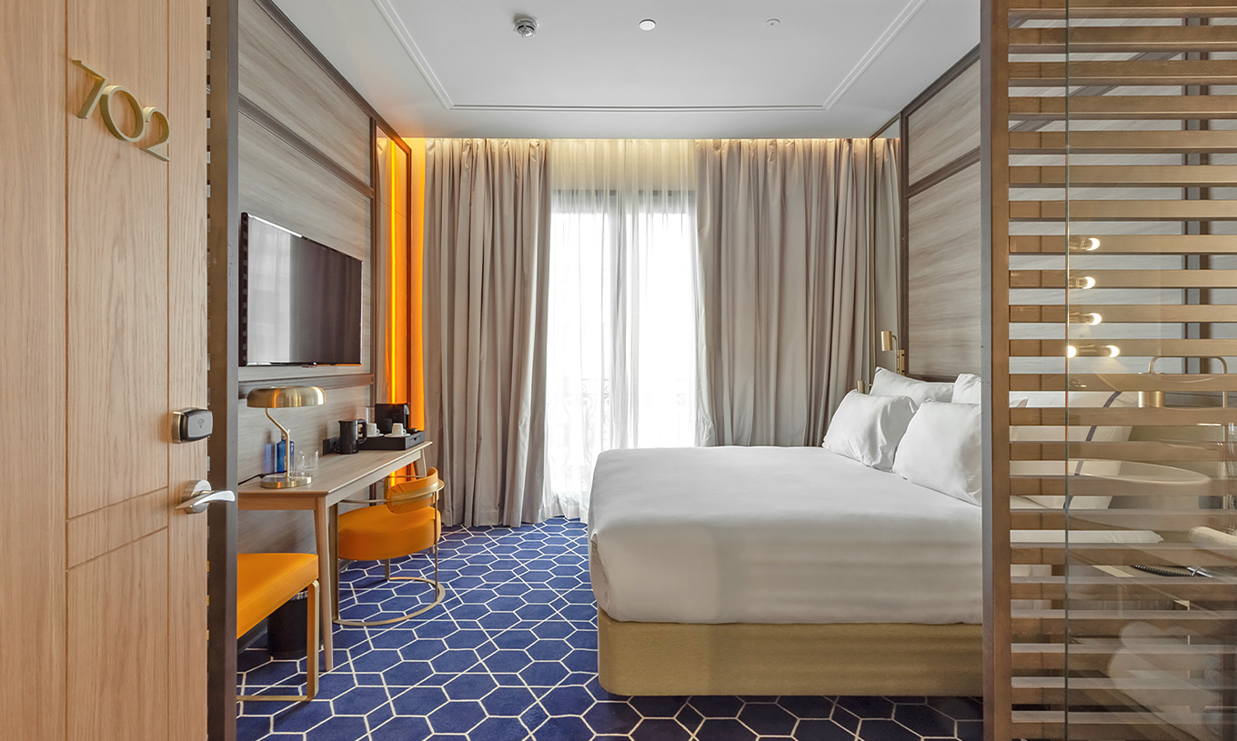 The Premium Room at Pestana CR7 Gran Vía Madrid includes a double bed, desk, chair, television, and curtained window