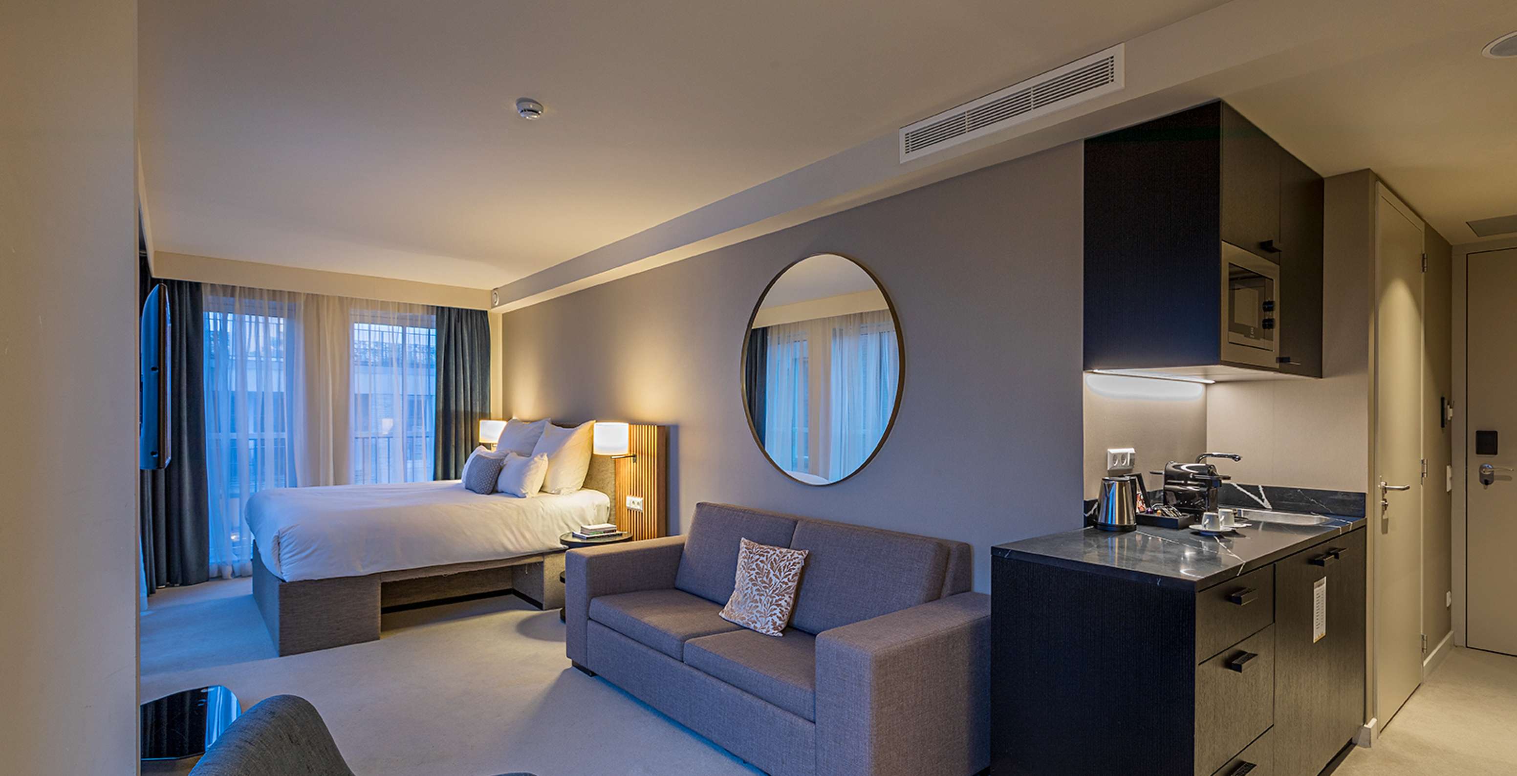 Comfort Studio room at Pestana Amsterdam Riverside has a double bed, with gray sofa and a mirror above