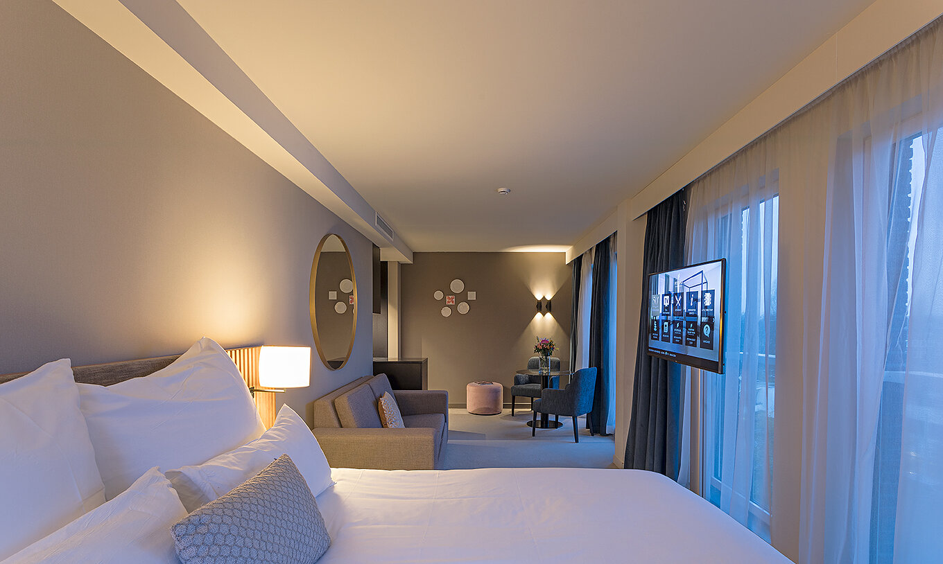 Premium Studio room at Pestana Amsterdam Riverside has a double bed, gray sofa, a mirror and two chairs