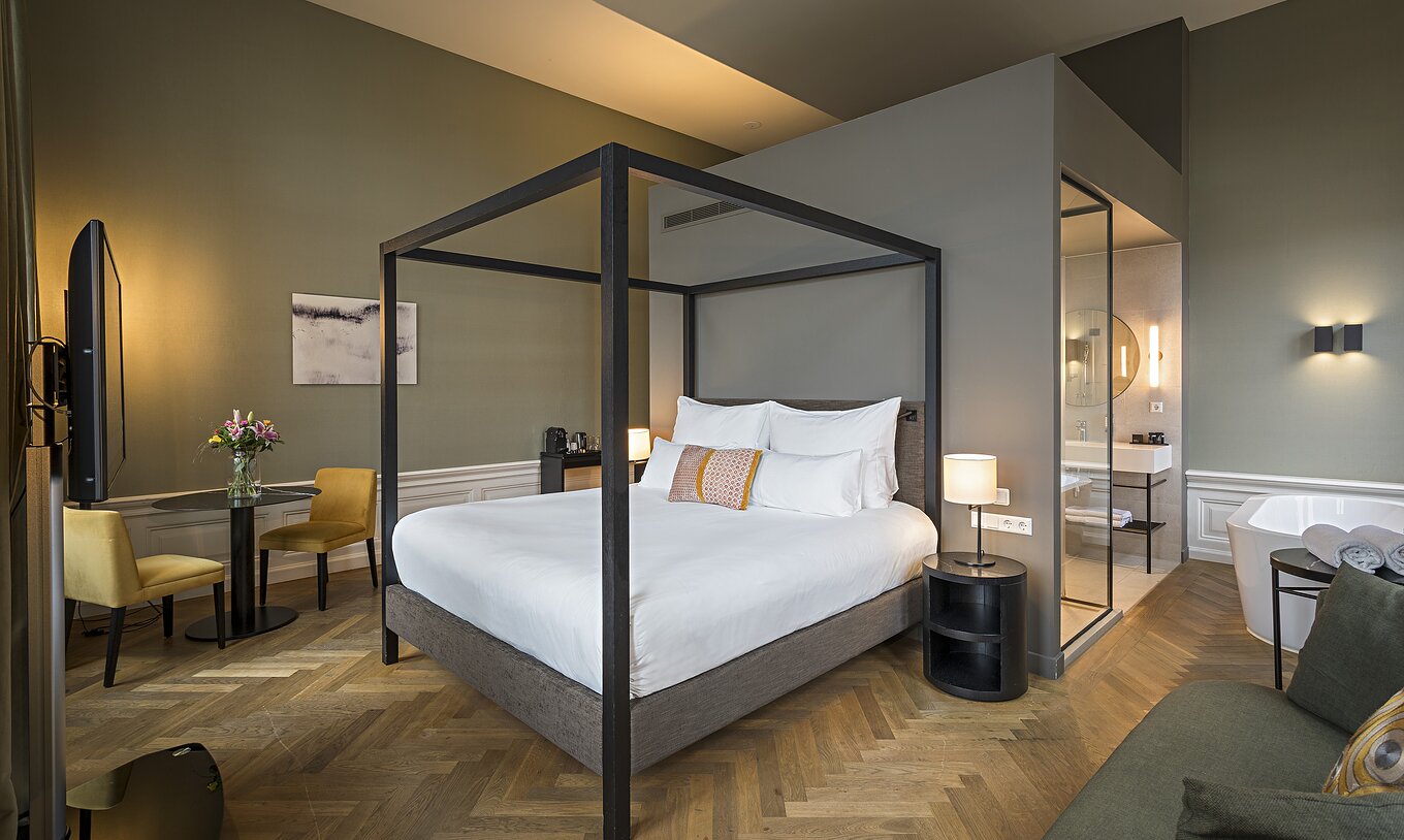 Junior Suite - River View at Pestana Amsterdam Riverside has a double bed with canopy and a table with two chairs