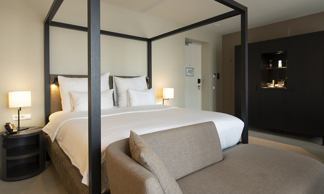 Premium Deluxe room at Pestana Amsterdam Riverside has a double bed with canopy, bedside table, and a sofa