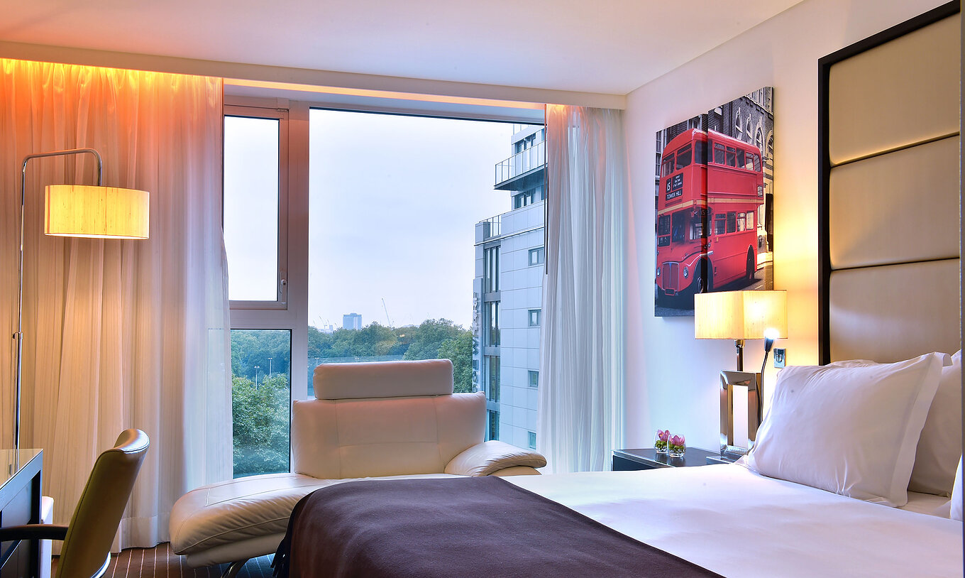 The Premium King at Pestana Chelsea Bridge has double bed, desk with chair, sofa and large window with view