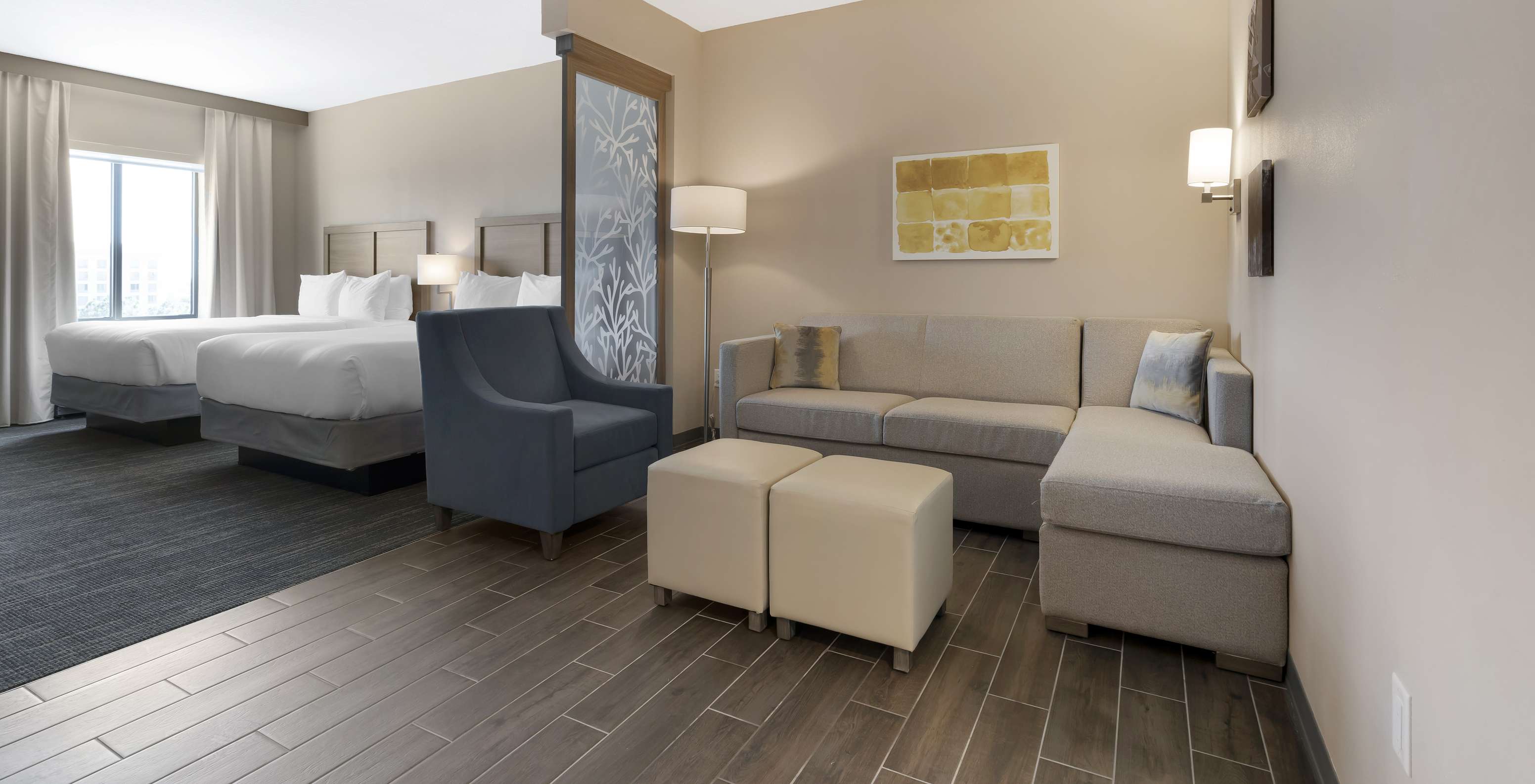 The Superior Double Queen Suite at Pestana Orlando Suites Lake Buena Vista includes two double beds, a sofa, and an armchair