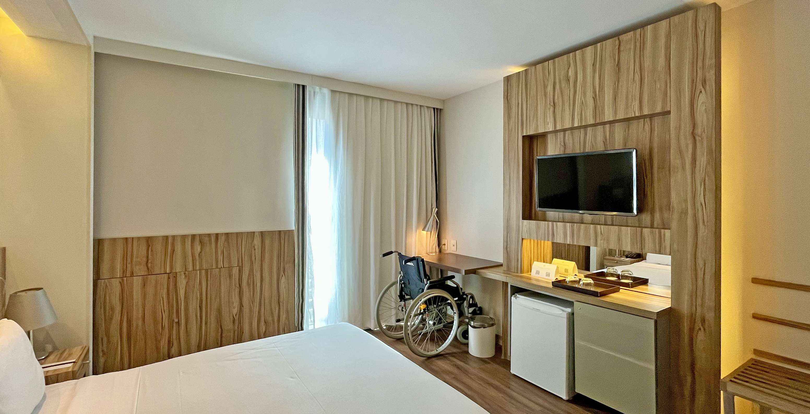 The Queen Disable Standard of Pestana Rio Atlântica has a double bed and a desk with a wheelchair