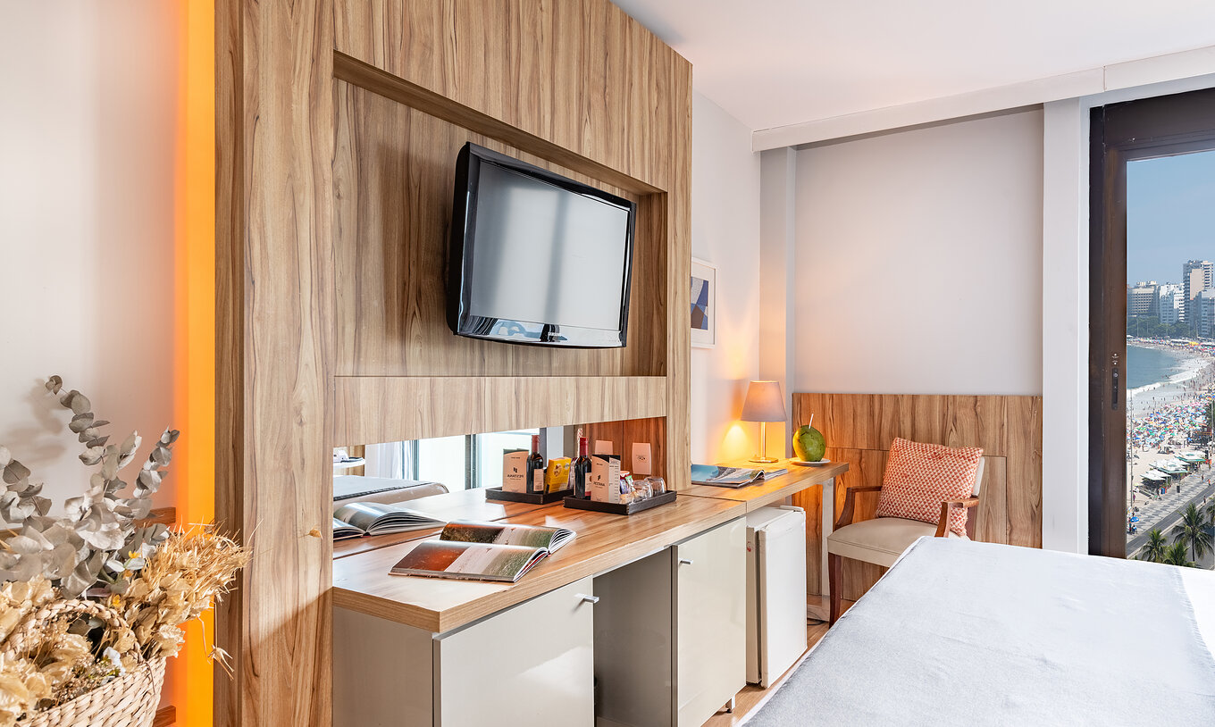 The Queen Side Sea View of Pestana Rio Atlântica has a television in front of the bed and a cushioned chair