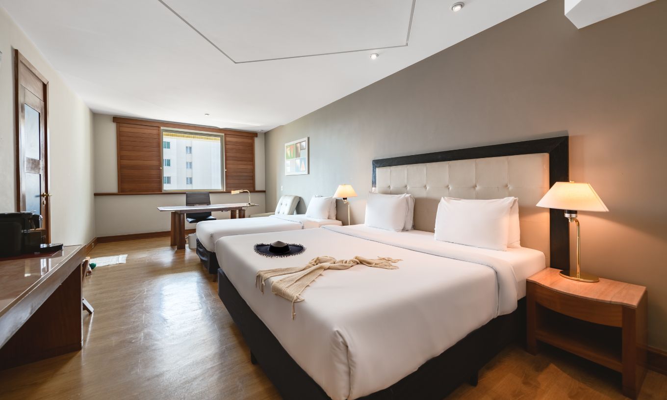 The Family Room at Pestana São Paulo has a double bed, two bedside tables, a desk, and a window