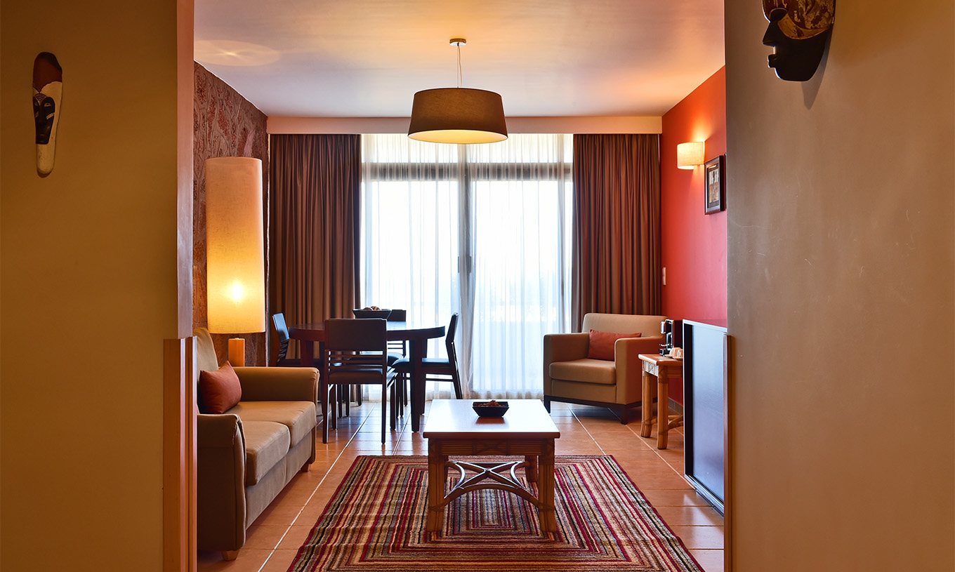 The Premium Suite at Pestana Tropico features a living room with sofa, dining table, armchair, and a coffee table