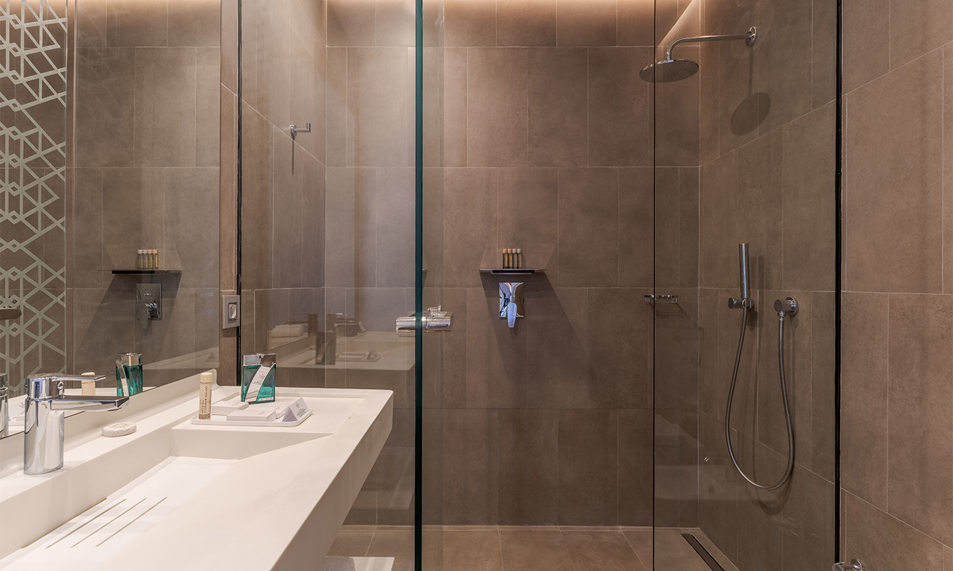 The CR7 Superior Avenue at Pestana CR7 Marrakech has a bathroom with a walk-in shower and a sink with a large mirror