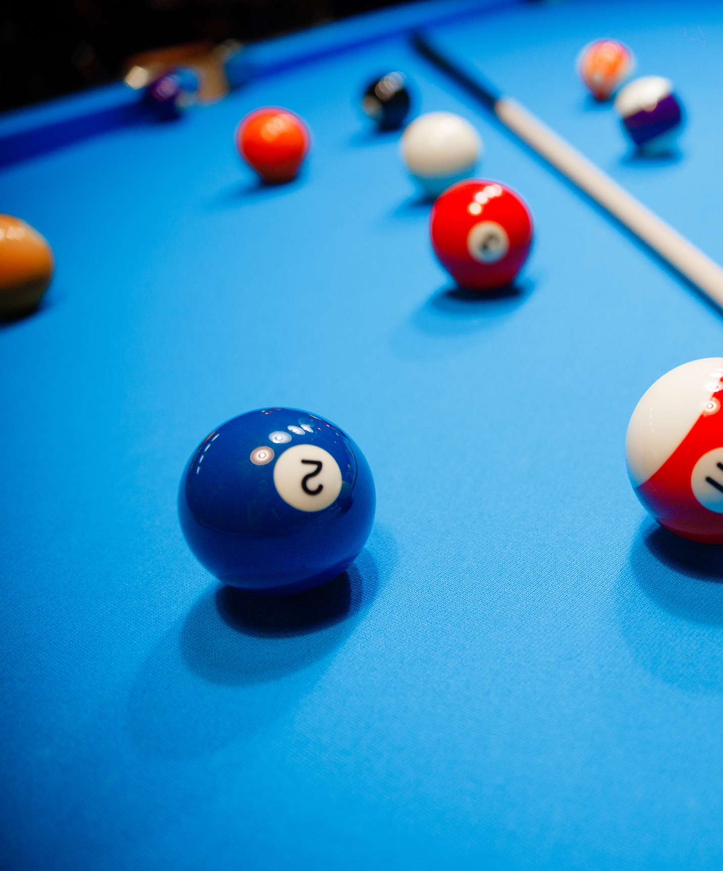 Pool table with several numbered balls scattered across the table and a cue in the middle at Pestana Tróia Eco Resort