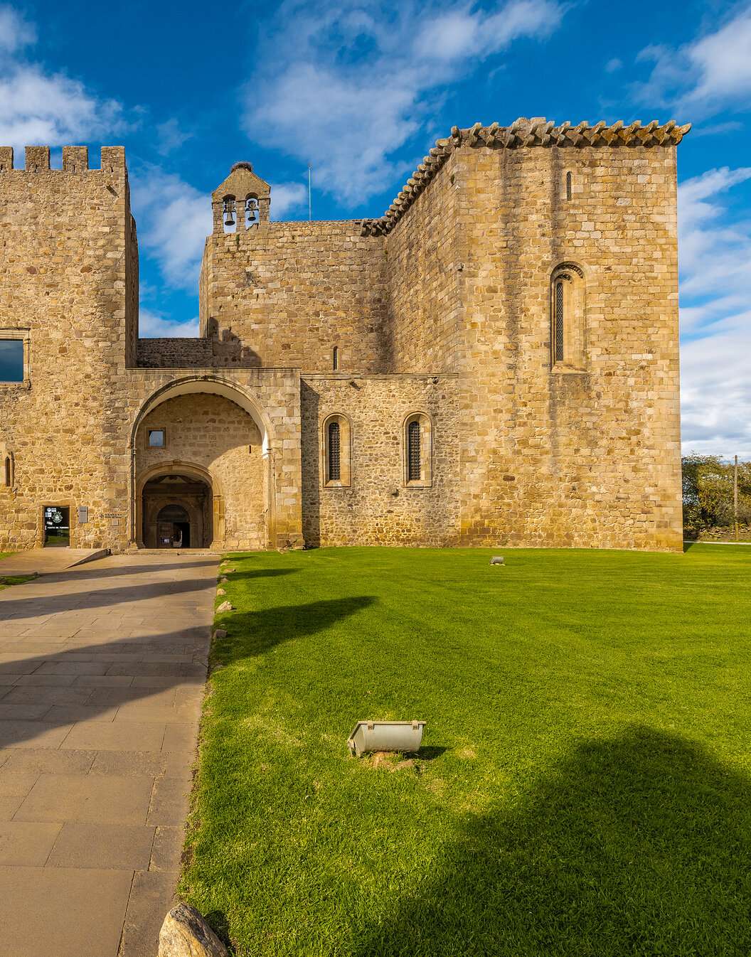 Exterior view of the stone facade of Pousada do Mosteiro do Crato, a historic hotel in Alentejo, with surrounding gardens