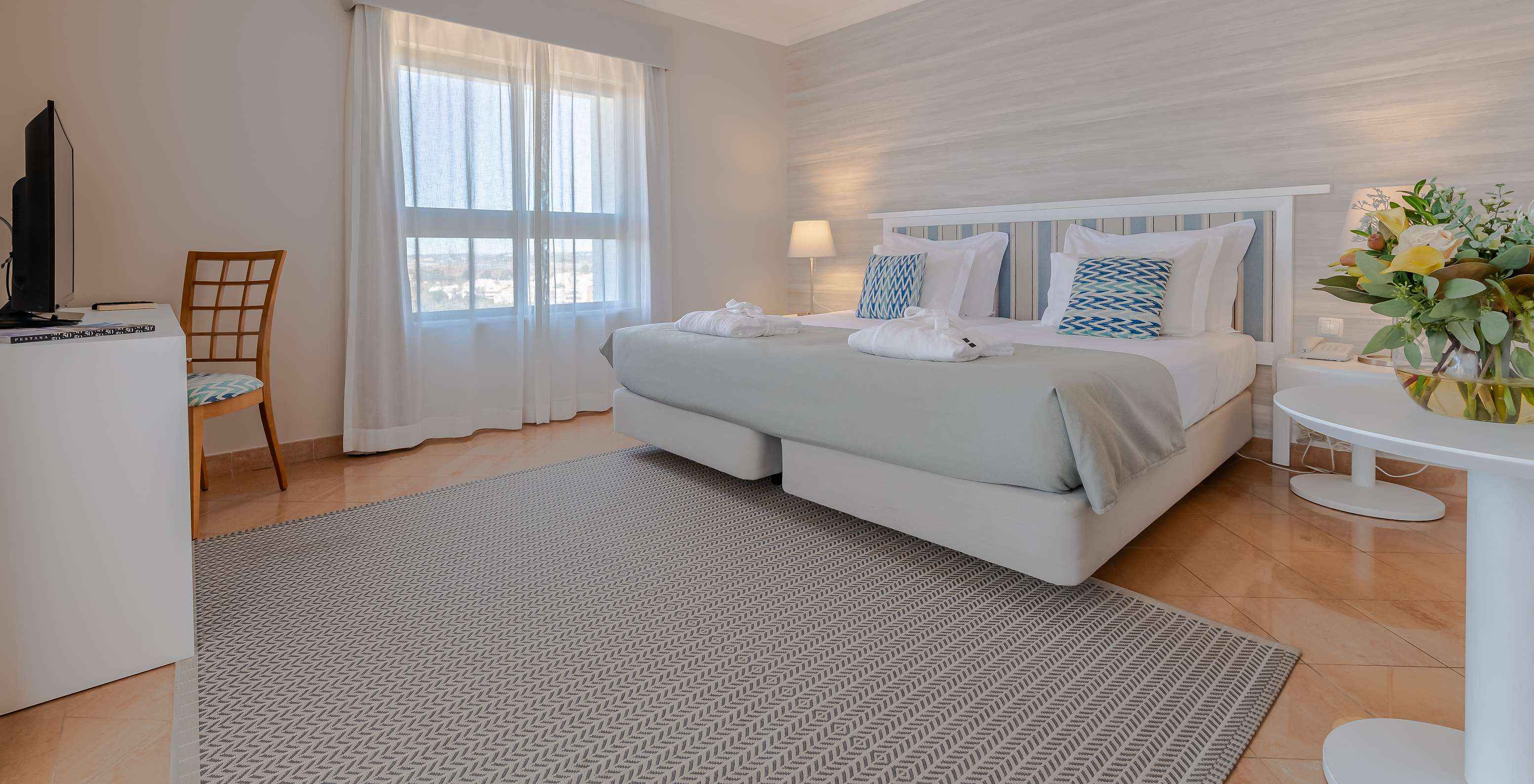 The T0 - Studio at Pestana Alvor Park has a double bed, a desk with a television, and a rug