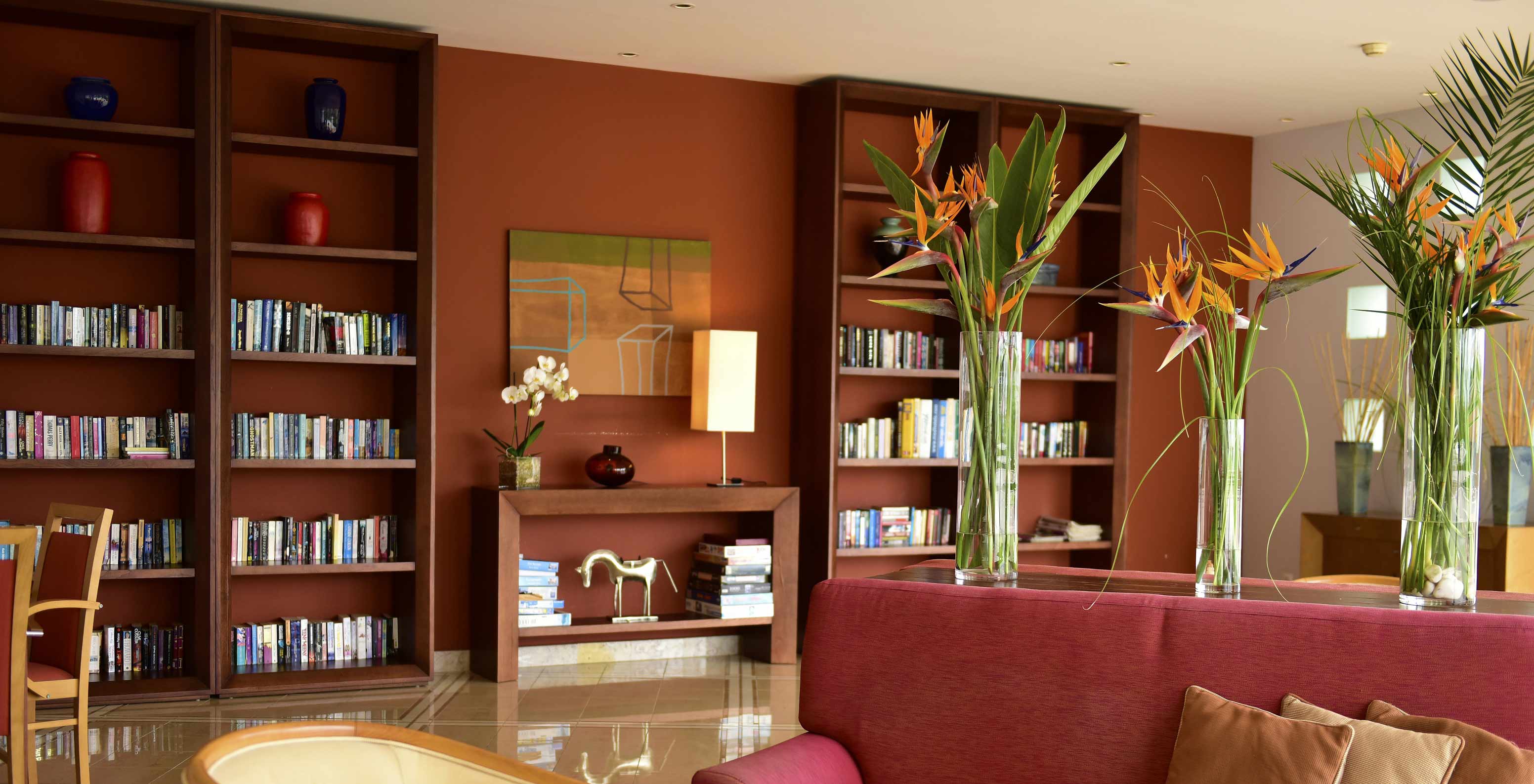 Library with bookshelves, flower vases, and a sofa at Pestana Alvor Park, a 4-star Aparthotel in Alvor with a swimming pool