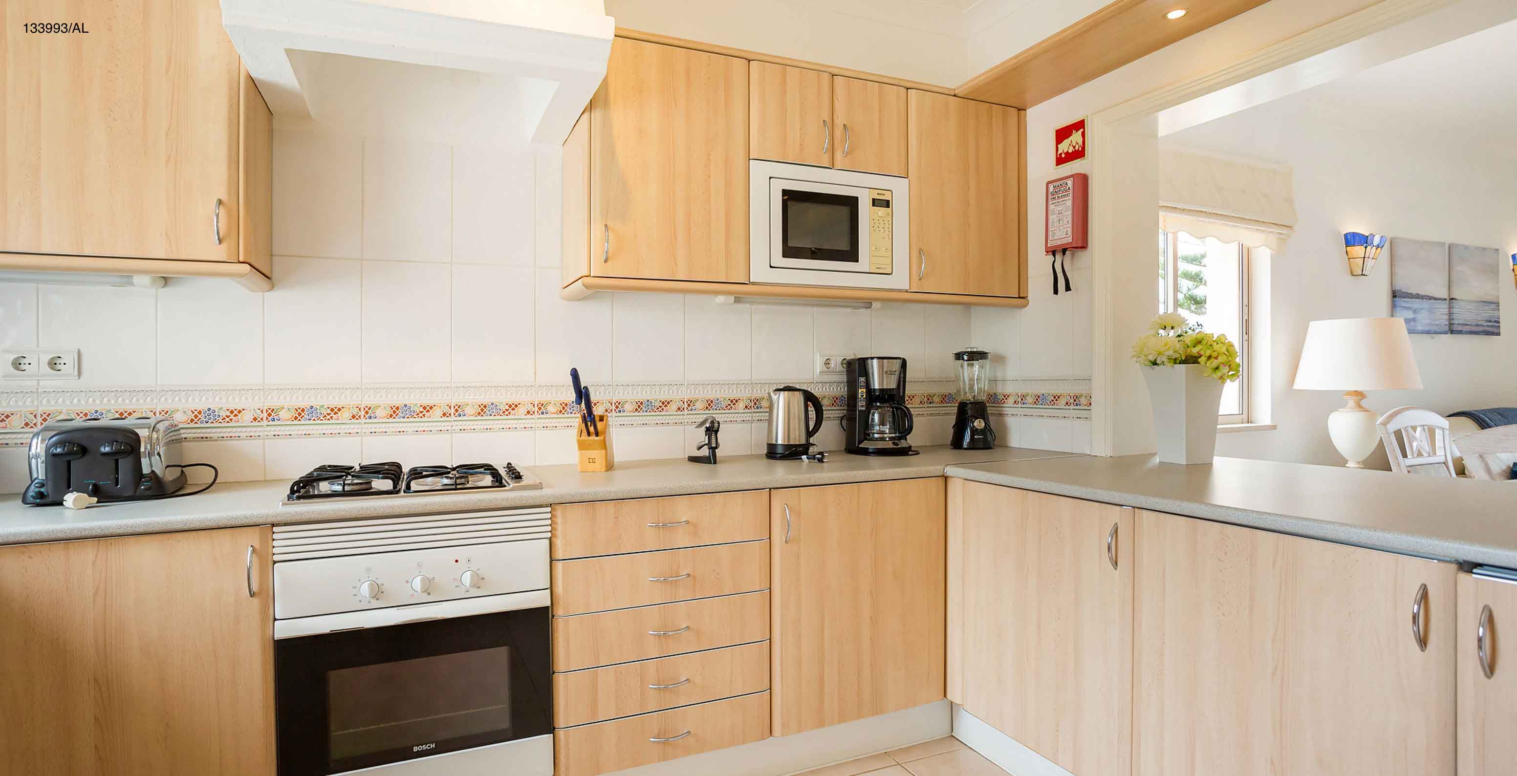 The Pestana Carvoeiro Golf T2 Superior Apartment has a kitchen with wooden cabinets and appliances