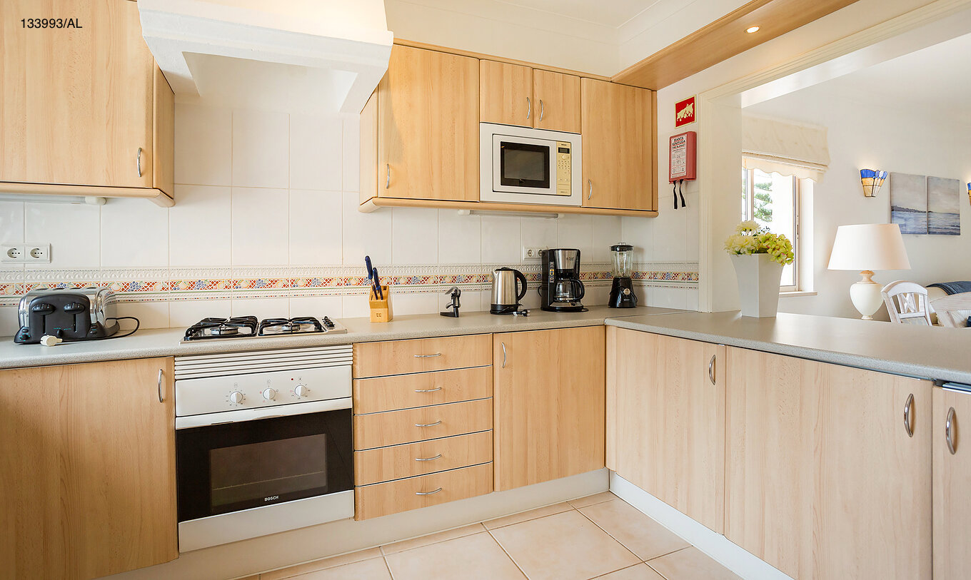 The Pestana Carvoeiro Golf T2 Superior Apartment has a kitchen with wooden cabinets and appliances