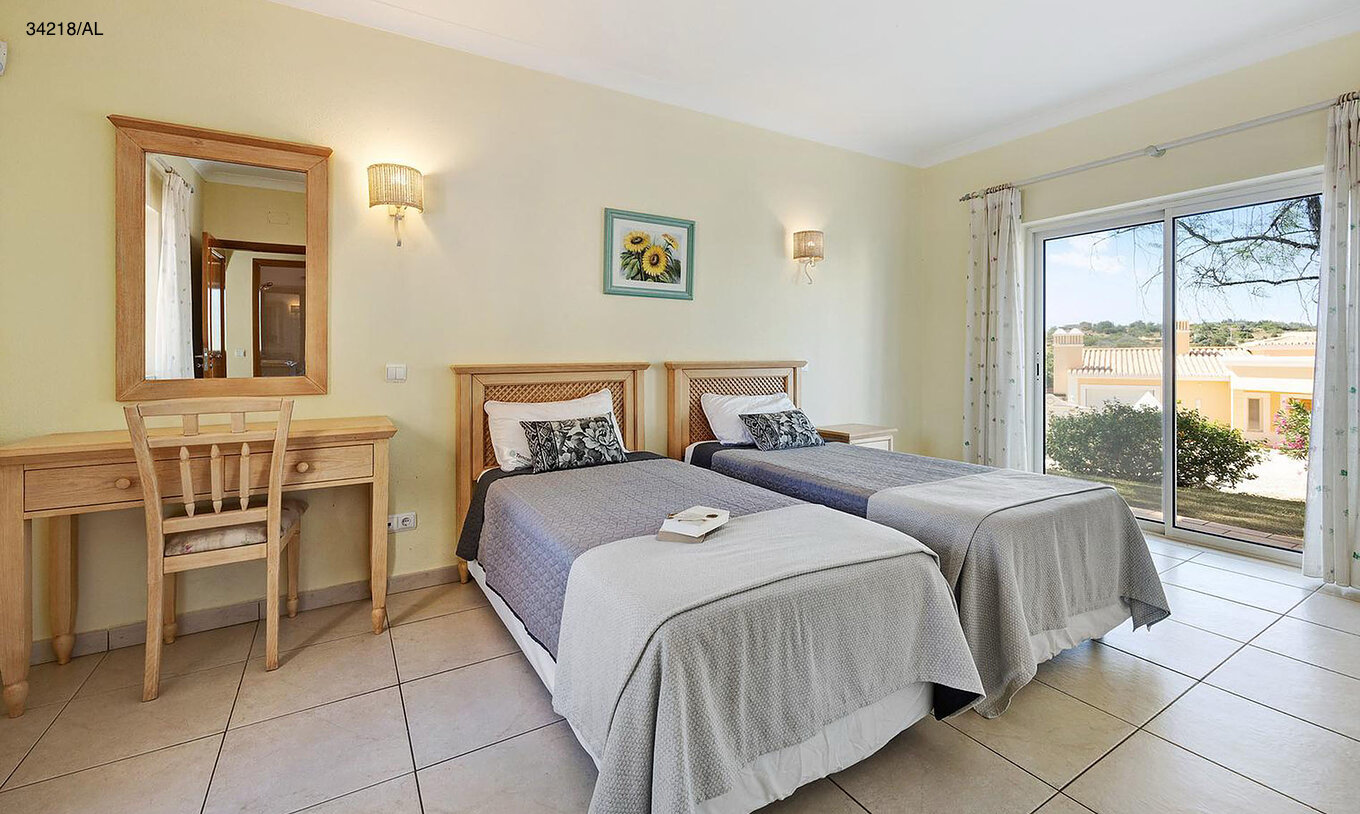 The Pestana Carvoeiro Golf V4 Standard Villa has a bedroom with two single beds, a mirror, and a table