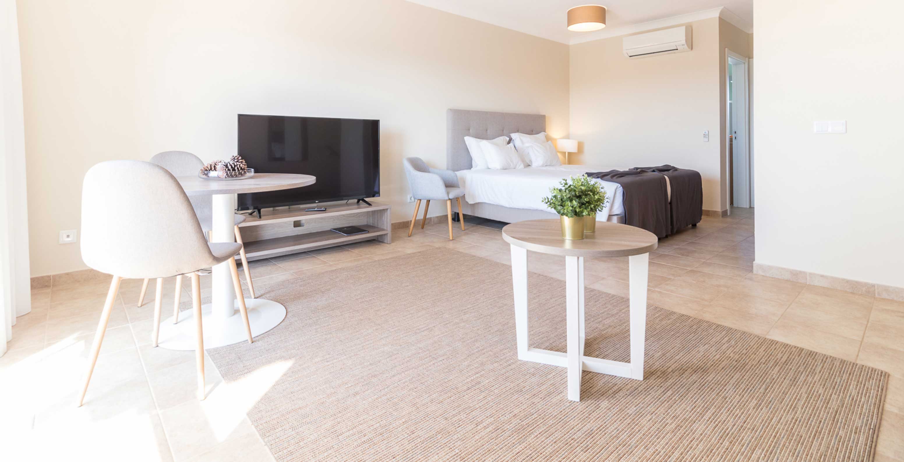 The studio at Pestana Gramacho Residences is modern with bed, TV, dining table and minimalist decor