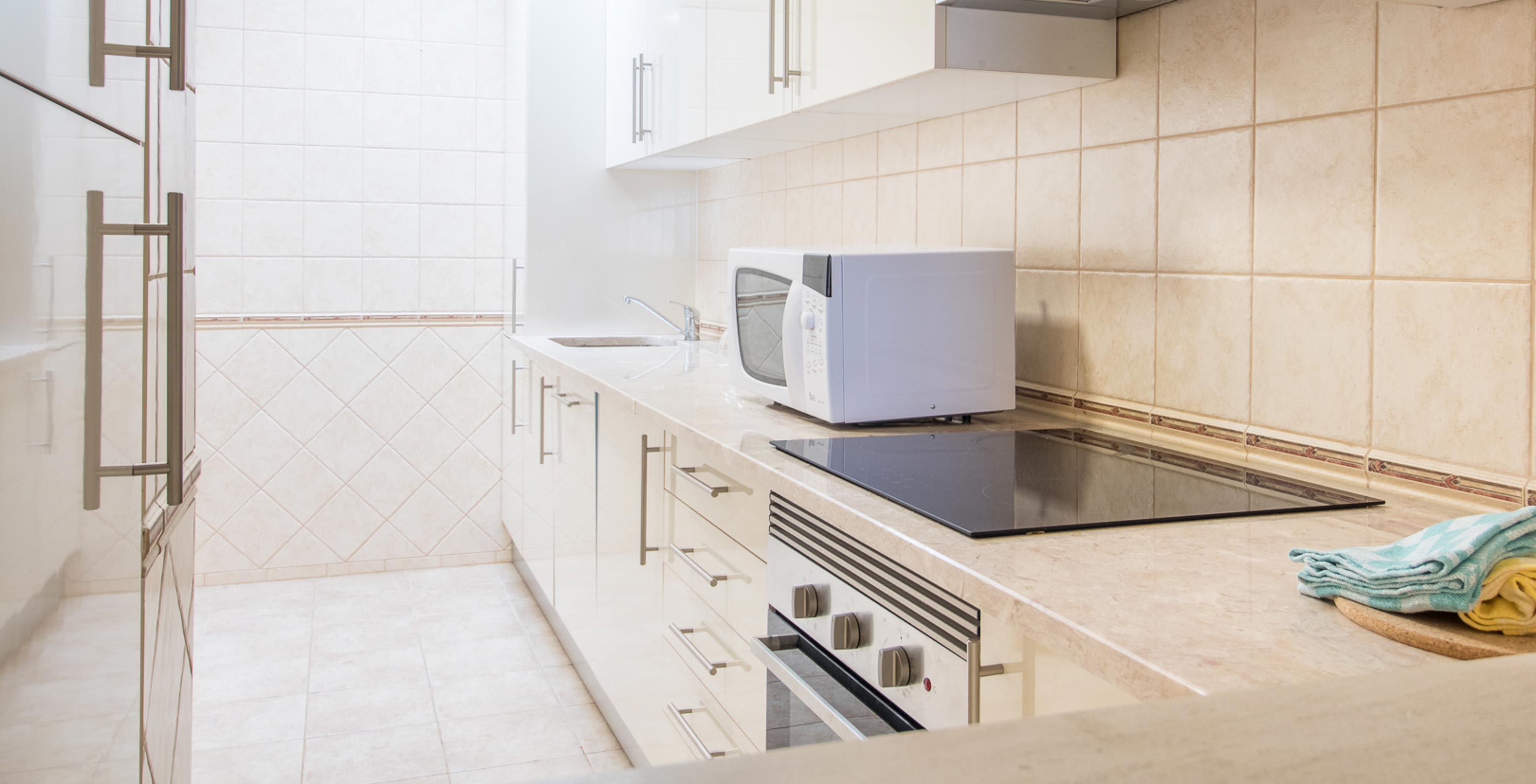 The one-bedroom apartment at Pestana Gramacho has a simple kitchen with appliances and neutral decor