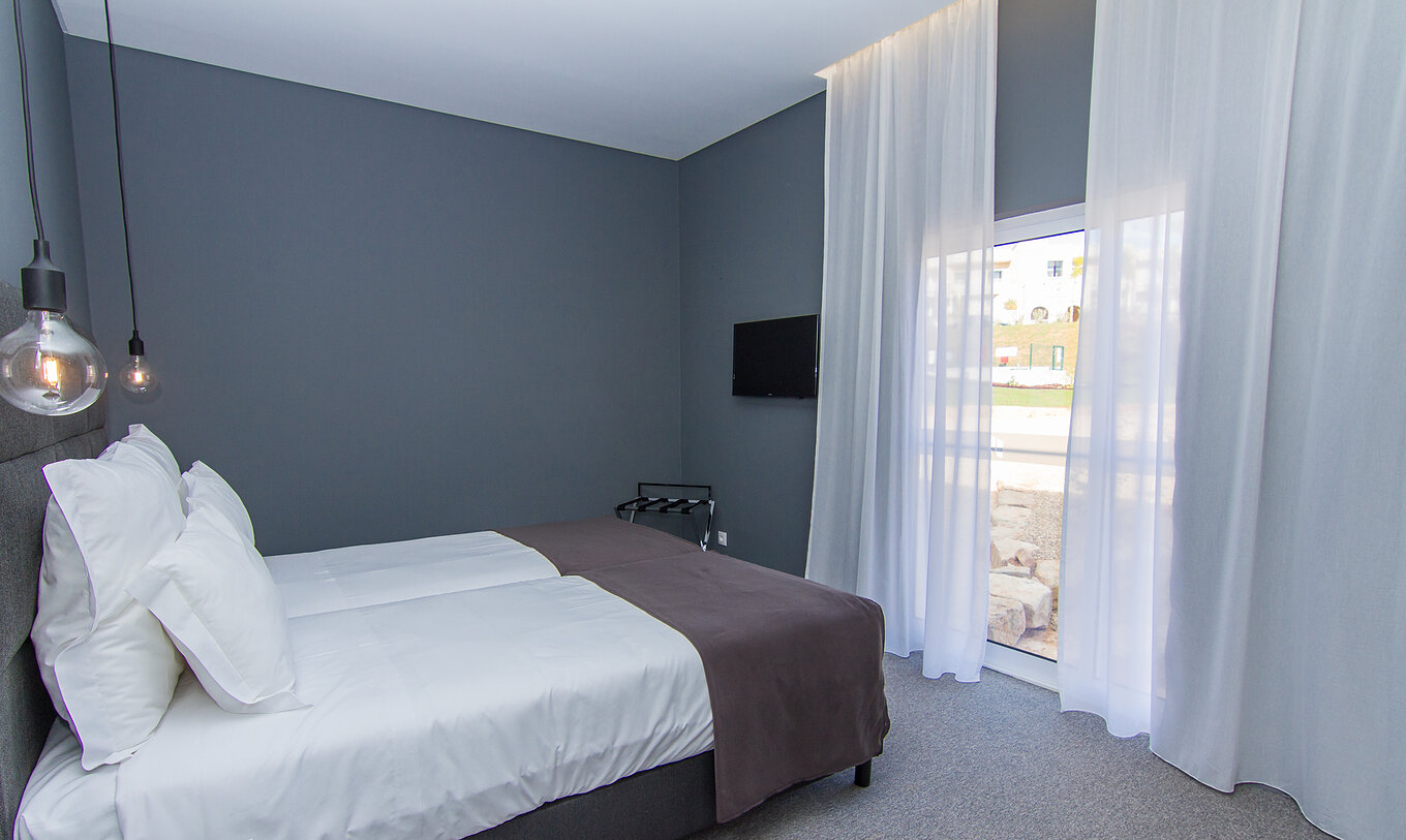 The Classic room at Pestana Gramacho Residences features two single beds, a television, and a window with curtains