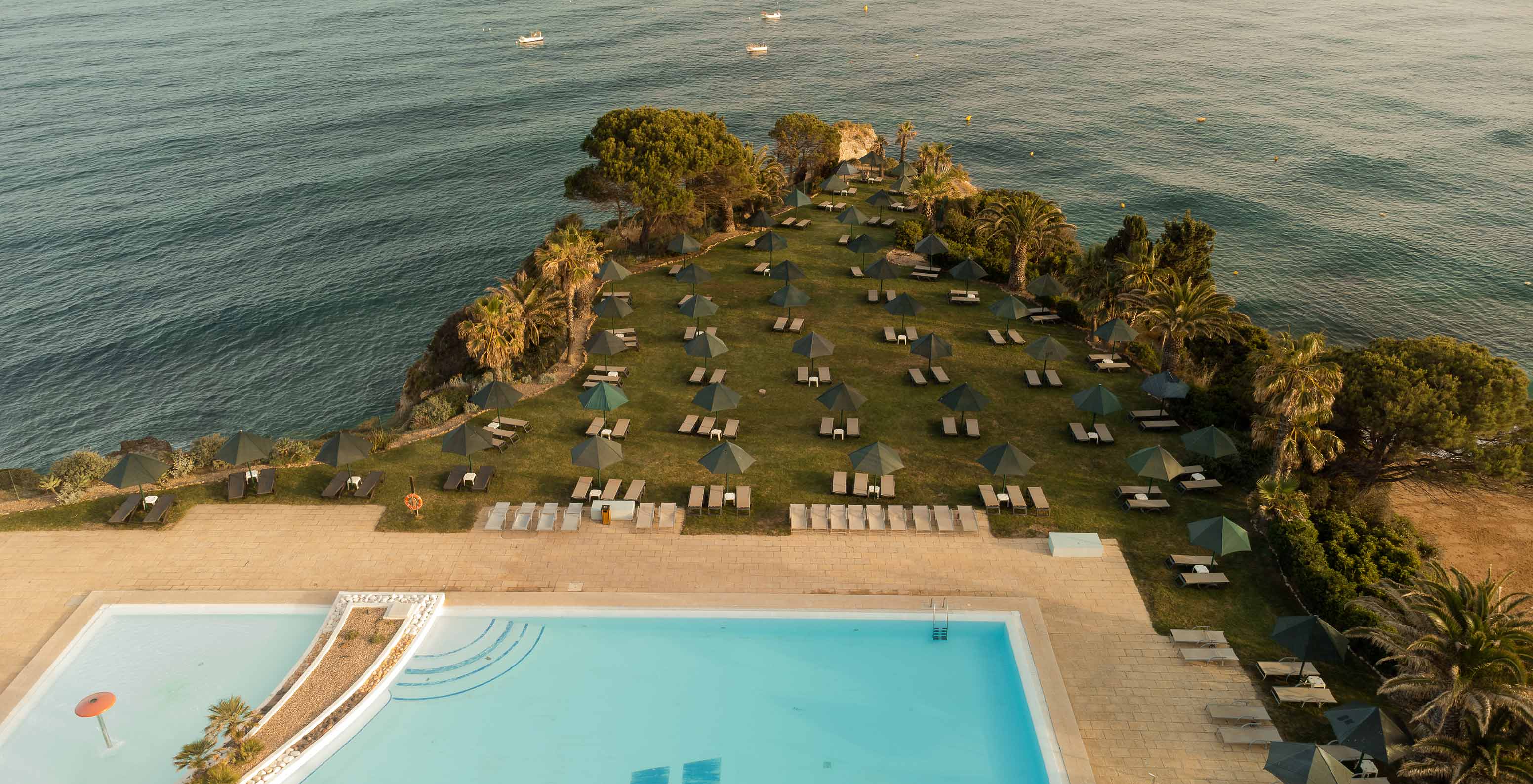 Outdoor pool at Pestana Viking, with sun loungers, surrounded by greenery and sea view