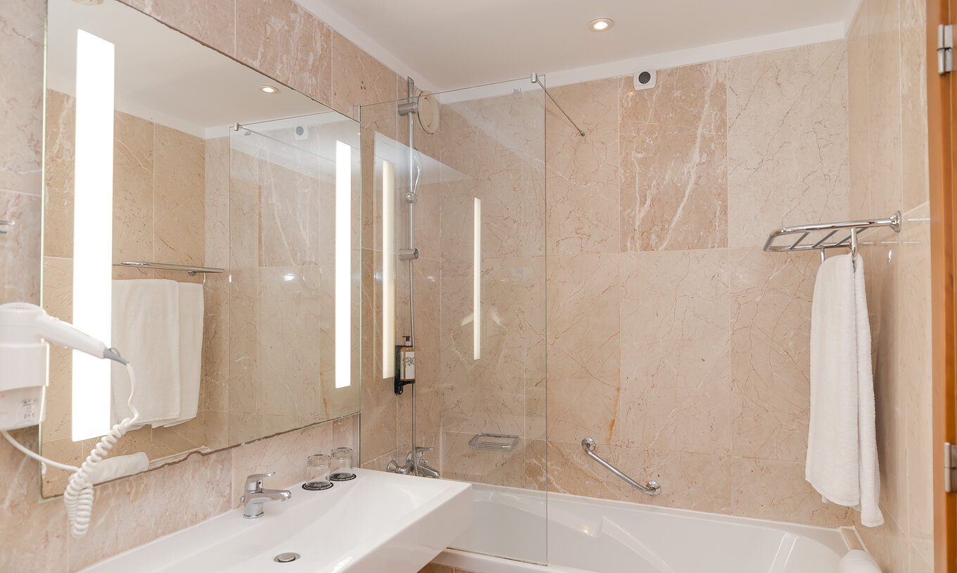 The Sea View Suite at Pestana Viking features a bathroom with sink, mirror, and bathtub with shower