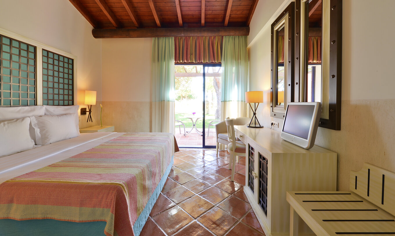 The Garden View Suite at Pestana Vila Sol - Vilamoura has a bedroom with a double bed, mirrors, and a window with a balcony