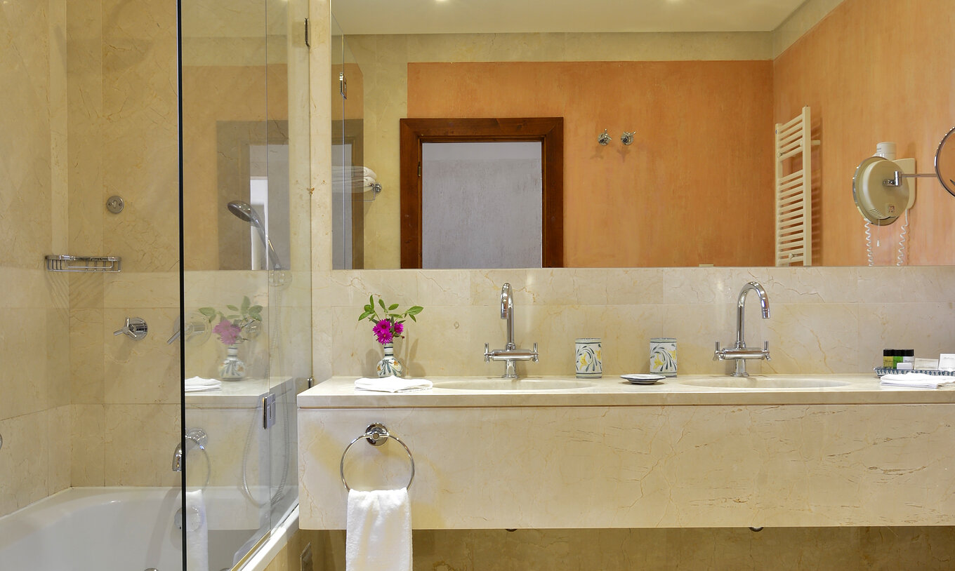 The Garden View Suite at Pestana Vila Sol - Vilamoura has a bathroom with a bathtub, two sinks, and a mirror
