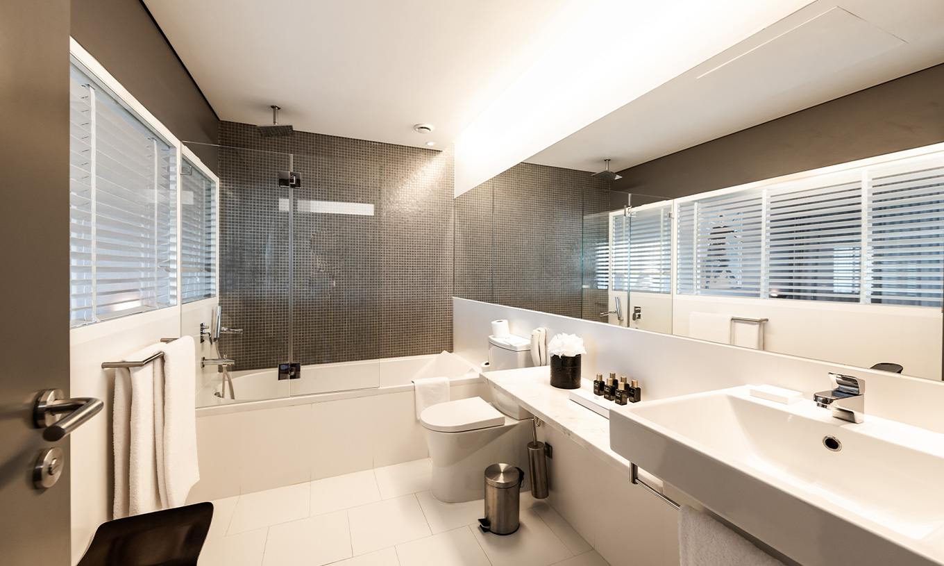The Suite at Pestana Cidadela Cascais has a large bathroom with a sink with a mirror, toilet, and a bathtub with a shower