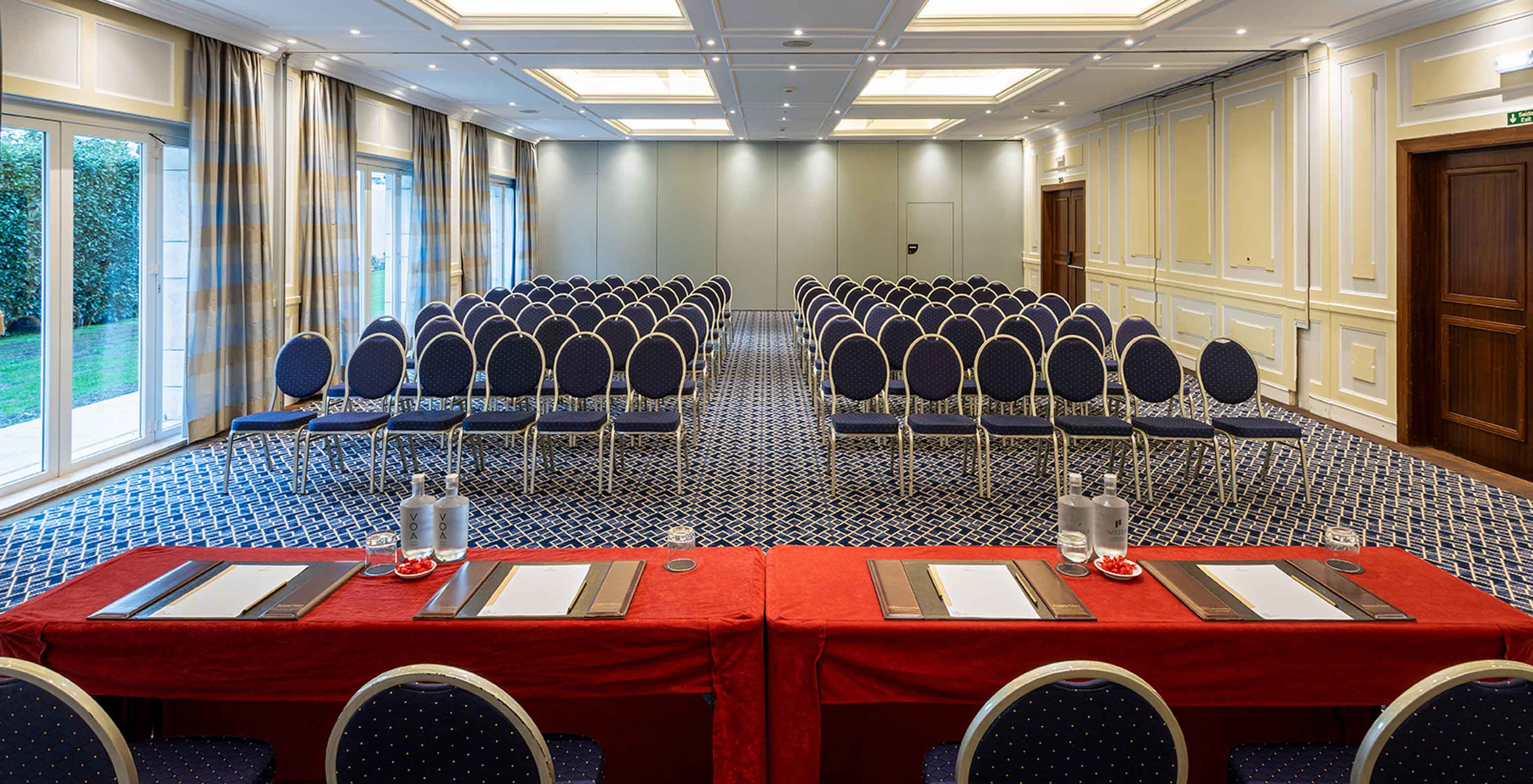 Pestana Palace Lisboa has a meeting room with blue carpet, red tables and long grey curtains