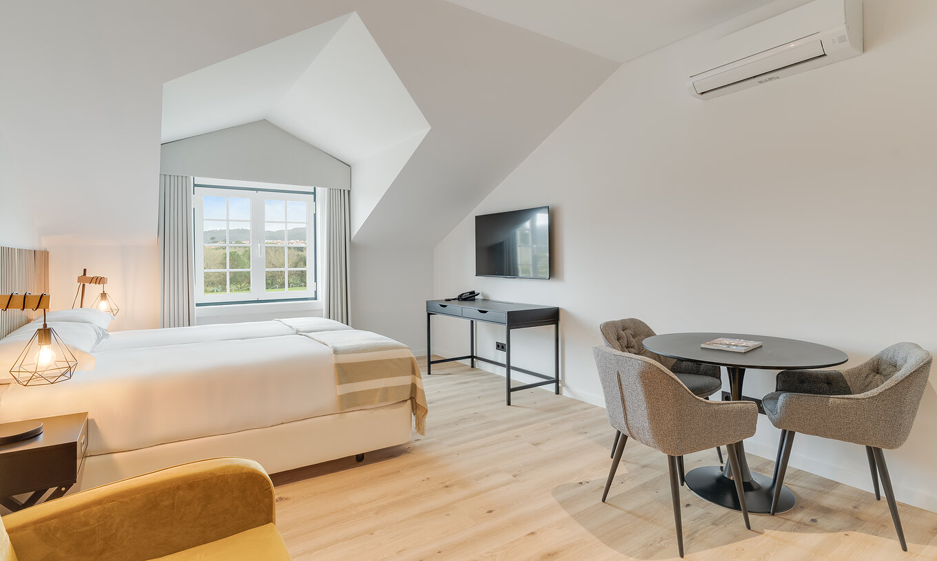 The Family - Clubhouse of Pestana Sintra Golf has two beds, a table with chairs, television, air conditioning, and a window