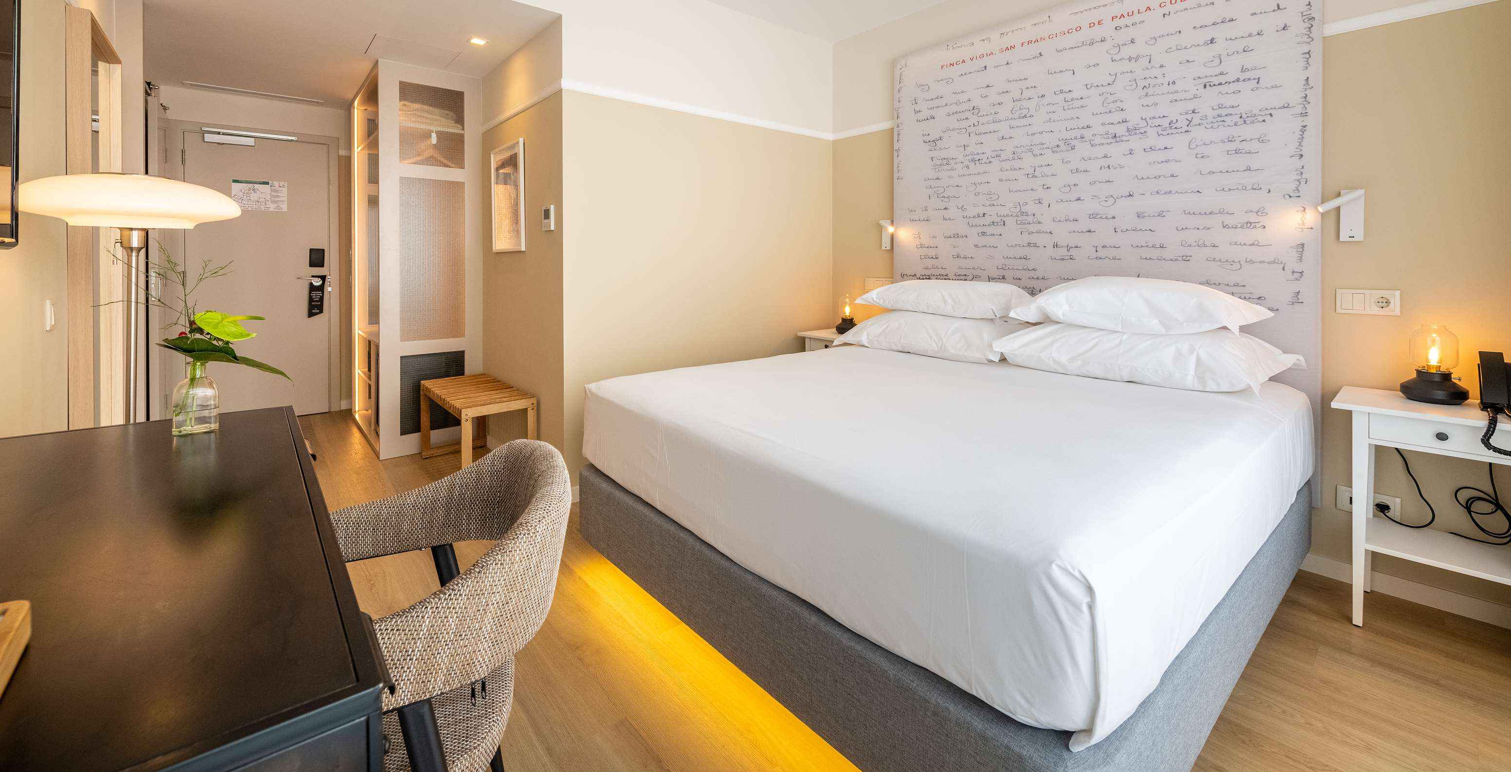 The Superior Room at Pestana Fisherman Village features a double bed with a headboard with written phrases and a desk