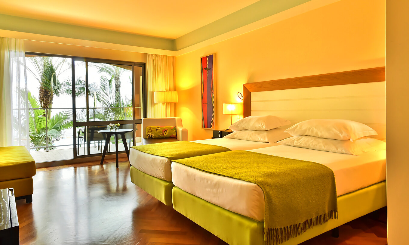 The Classic Sea View of Pestana Promenade has two beds with a green bedspread and a large window to the balcony