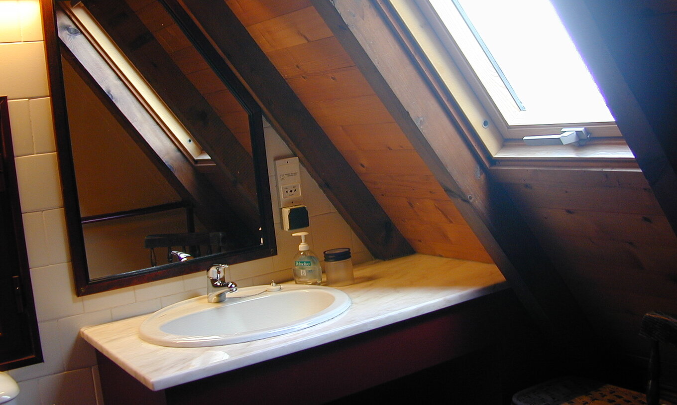 The Duplex Villas of Pestana Quinta do Arco have a bathroom with sink and sloped window, with mirror and wooden ceiling