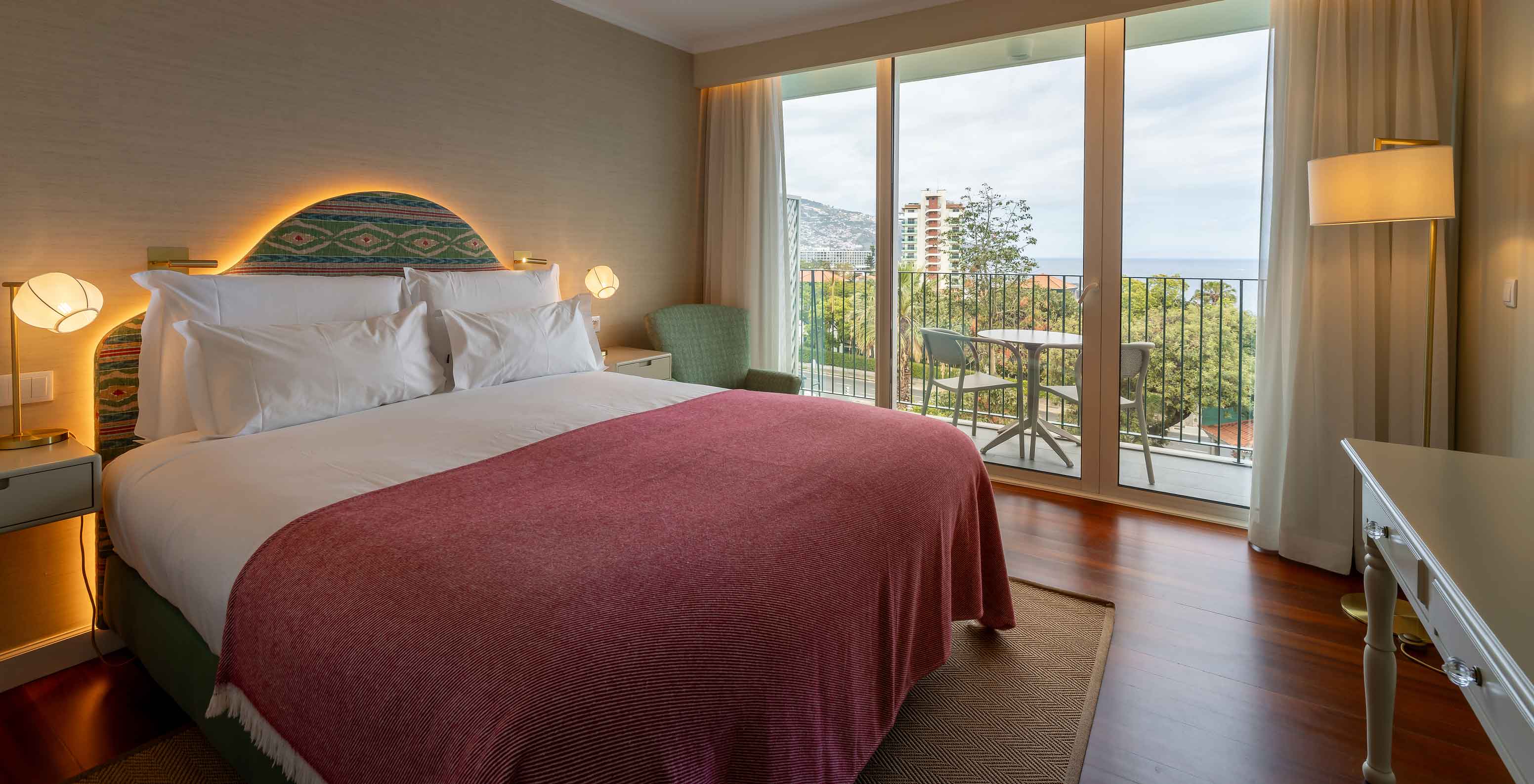 The Partial Sea View Room at Pestana Quinta Perestrello has a double bed, a balcony with a table, chairs, and a sea view.
