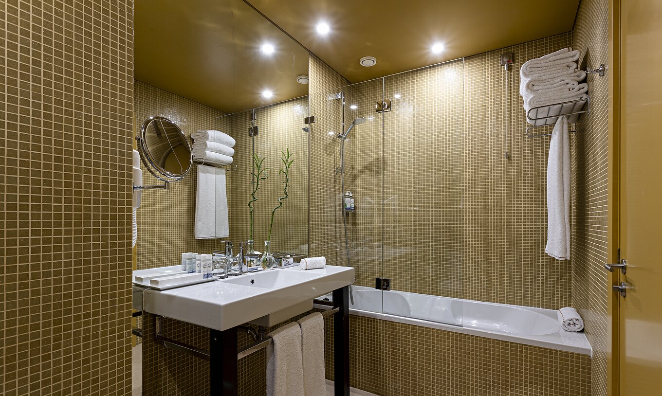 The Junior Suite has a bathroom with yellow tiles, a sink, and a bathtub