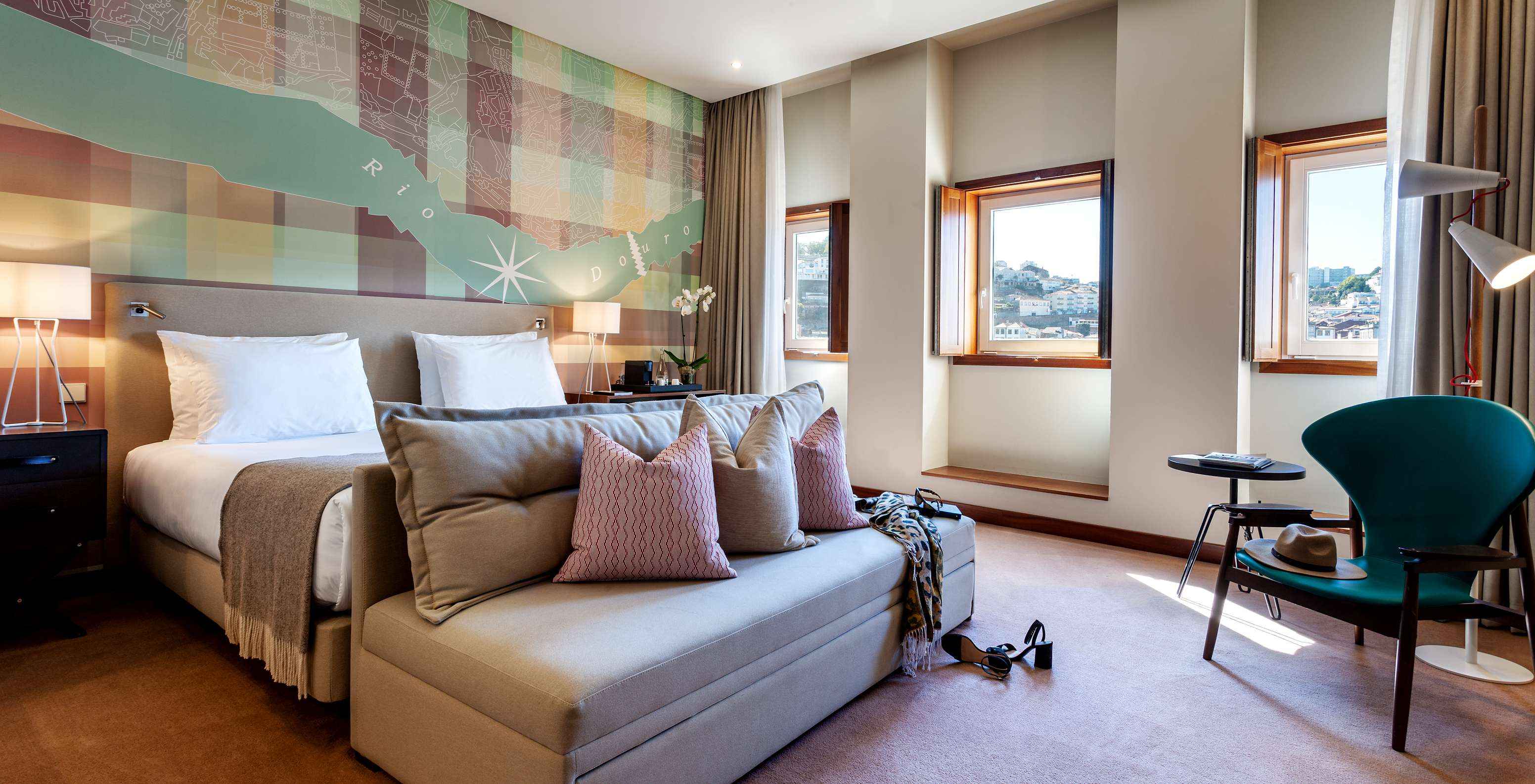 The Vintage Front View room at Pestana Vintage Porto has a double bed with a sofa at the foot, three windows and an armchair