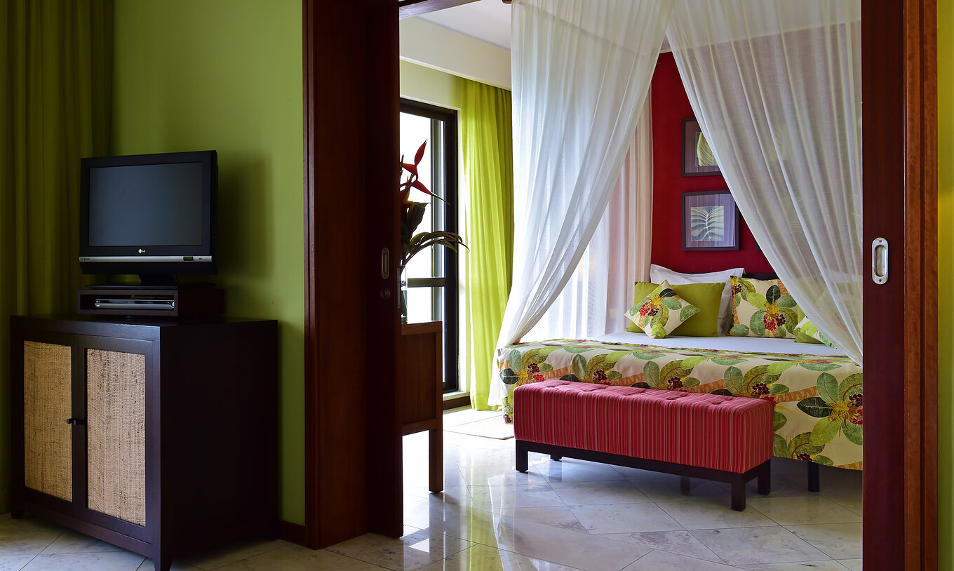 The Central Suite of Pestana São Tomé has a king-size double bed with a canopy and an ottoman at the foot
