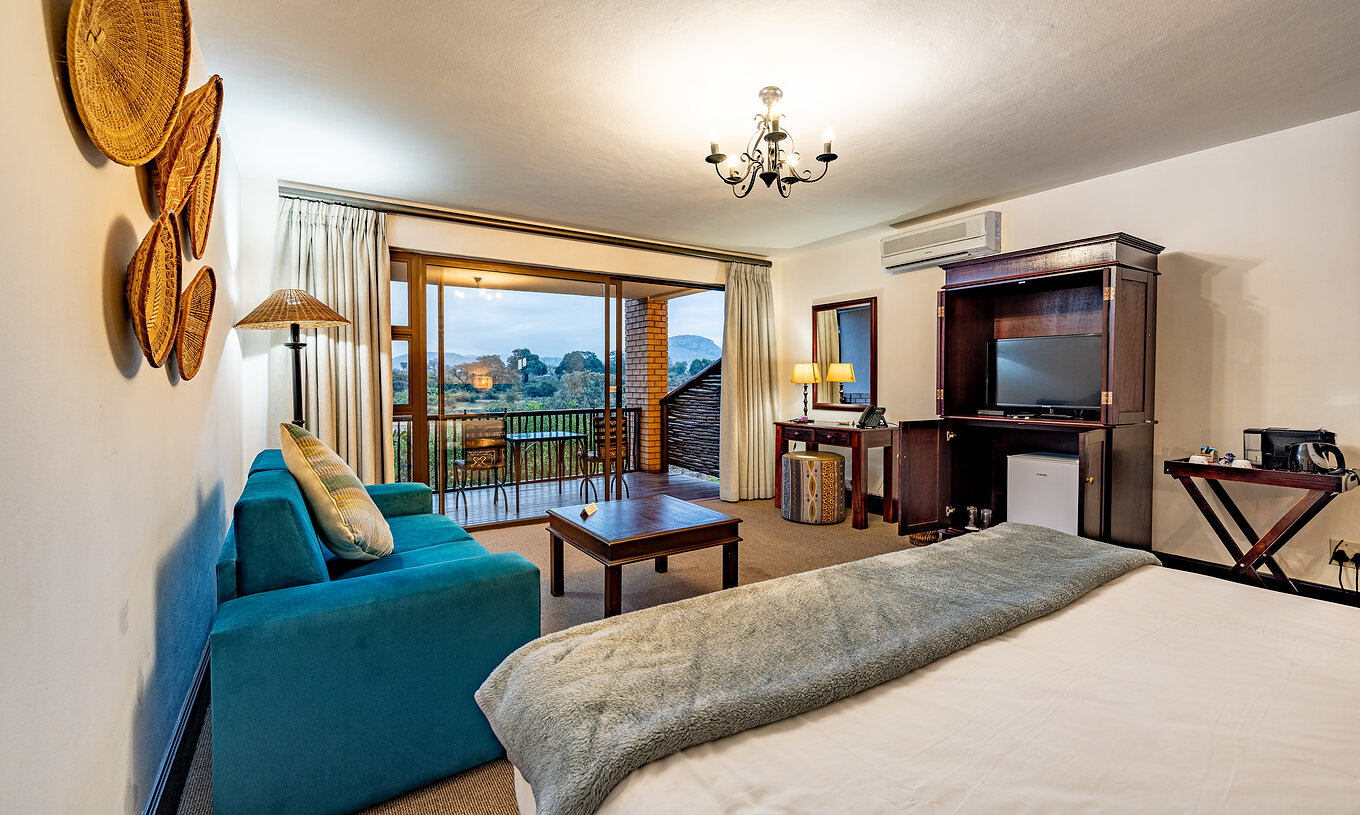 The Premium Room at Pestana Kruger Lodge has a seating area with sofa, TV and typical African decor