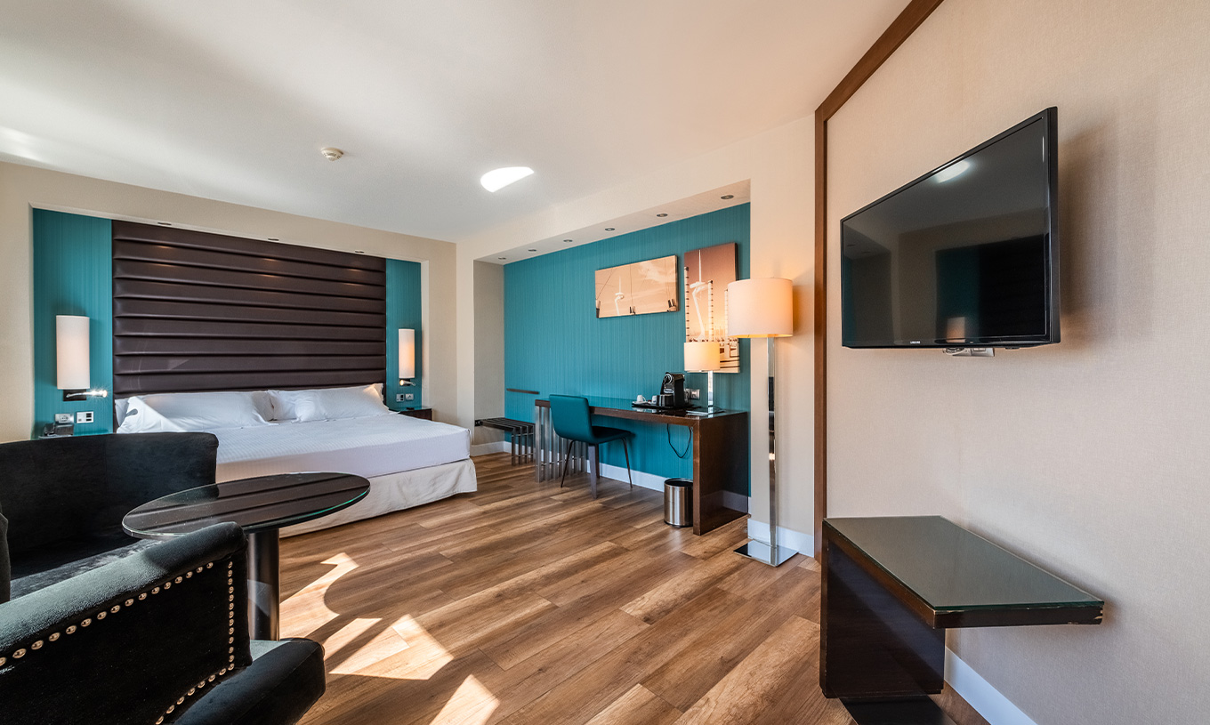 Junior Suite at Pestana Arena Barcelona has a spacious room with a TV in front of the sofa and a double bed