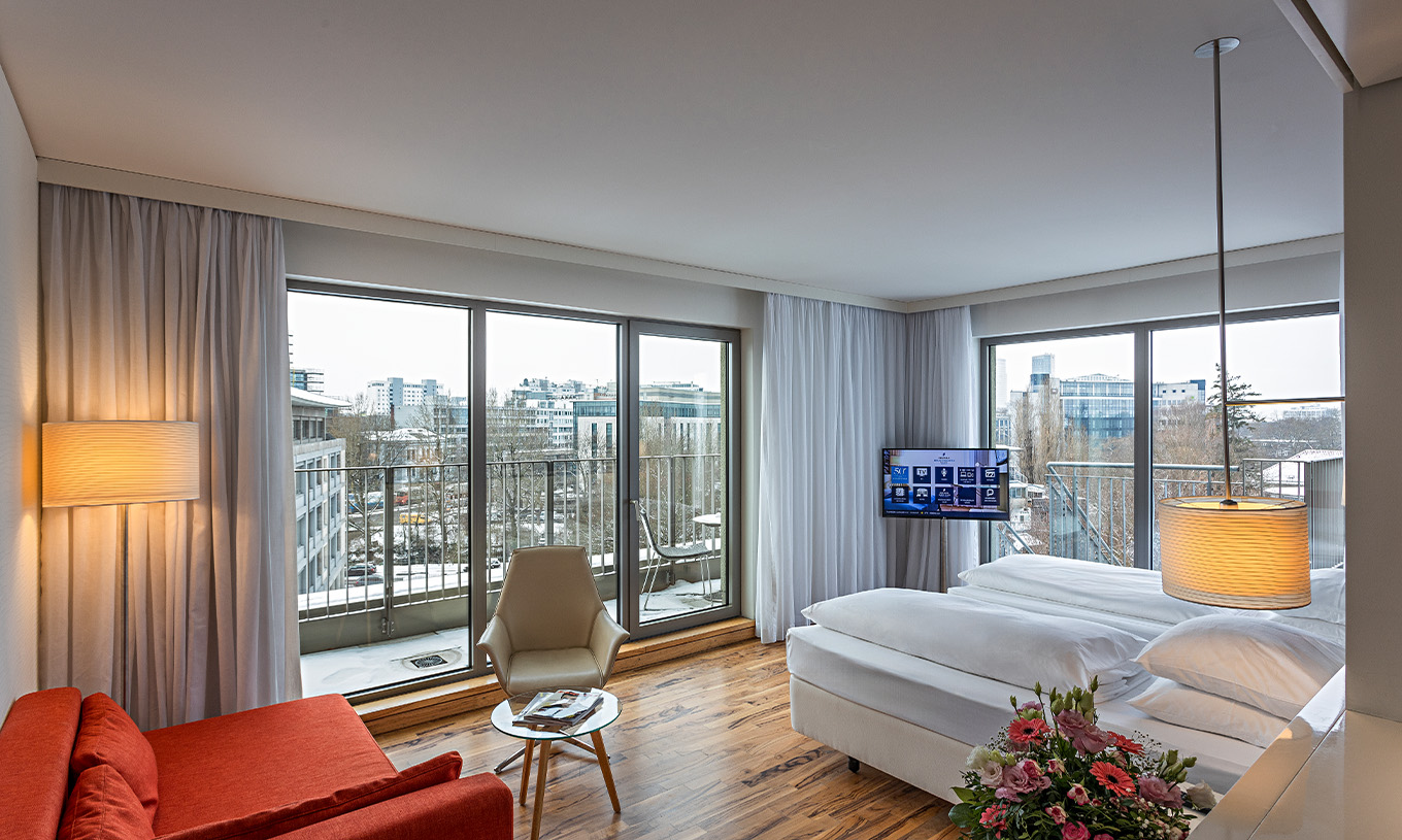 El Cuarto Premium con Balcón Panorámico del Pestana Berlin Tiergarten tiene sofá con lámpara, televisión y cama