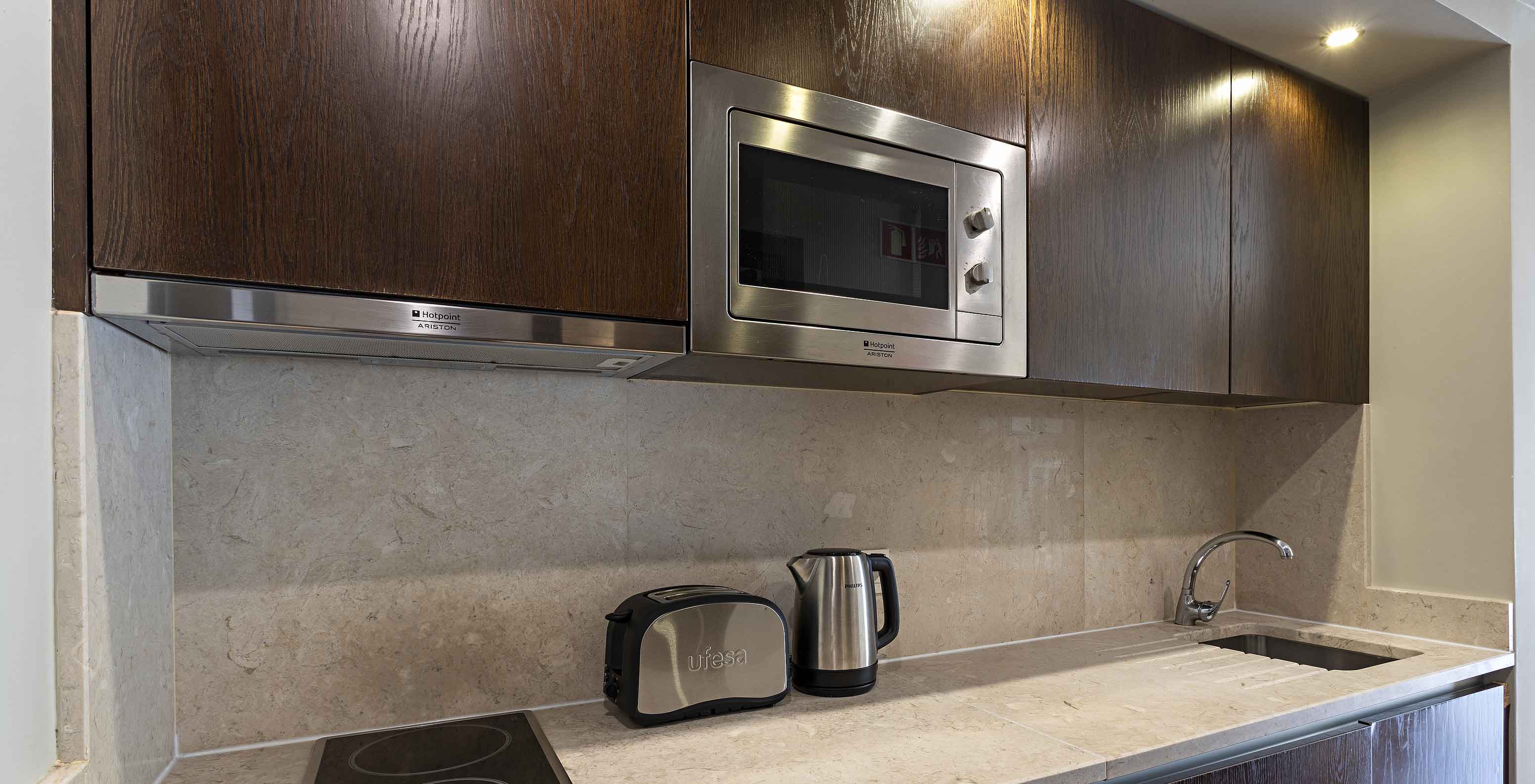 La Cliff Studio en Pestana Alvor Praia tiene una cocina equipada en madera oscura y piedra, con una estufa y un microondas