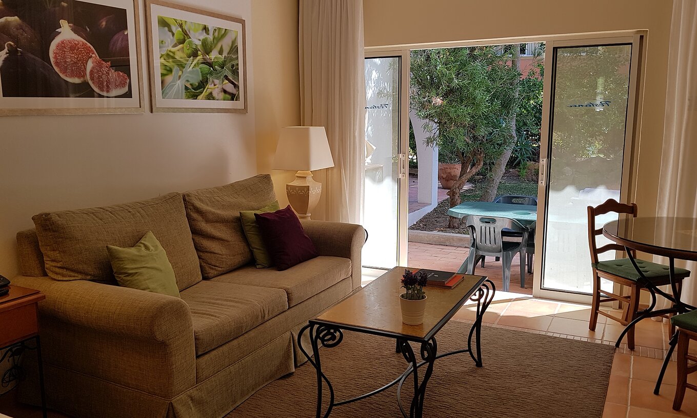 El Estudio del Pestana Palm Gardens tiene una sala de estar con sofá y una ventana que da acceso al jardín