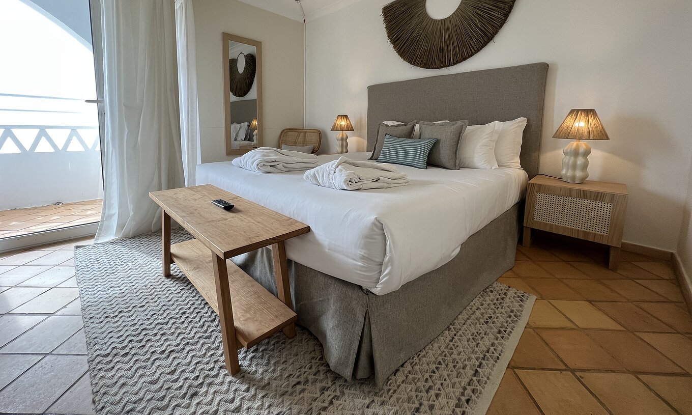 El Apartamento T2 Premium del Pestana Palm Gardens tiene una cama con dos batas, almohadas y una ventana con terraza