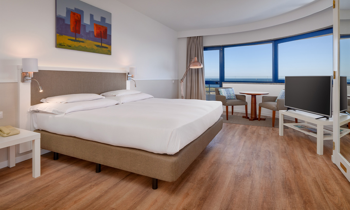 La Suite Deluxe Vista Mar del Pestana Cascais cuenta con cama de matrimonio, televisión y un cuadro pintado en la pared