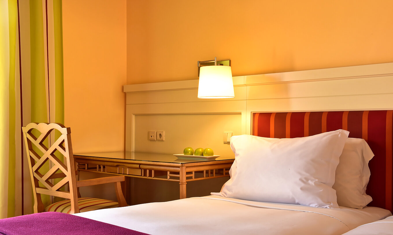 El Duplo Clássico del Pestana Sintra Golf tiene una cama con sábanas blancas y almohada, y un escritorio con silla