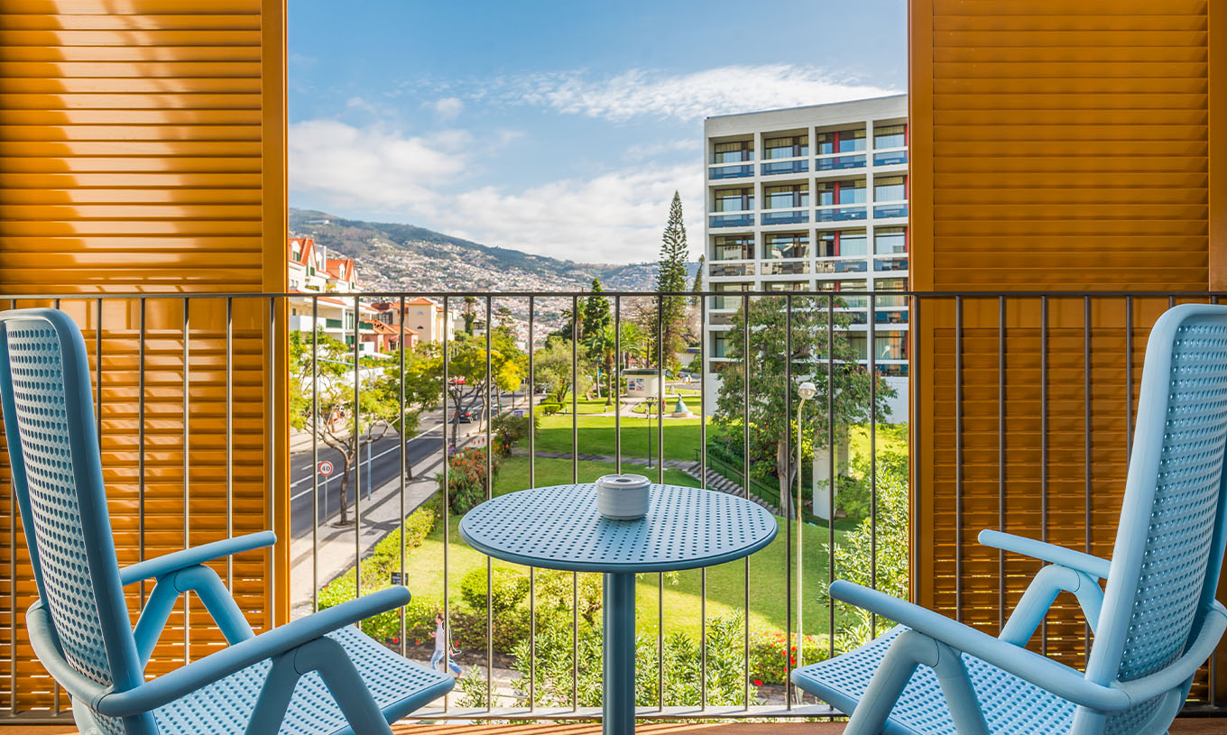 The Deluxe Studio at Pestana Casino Studios has a balcony with a city view and a table with blue chairs