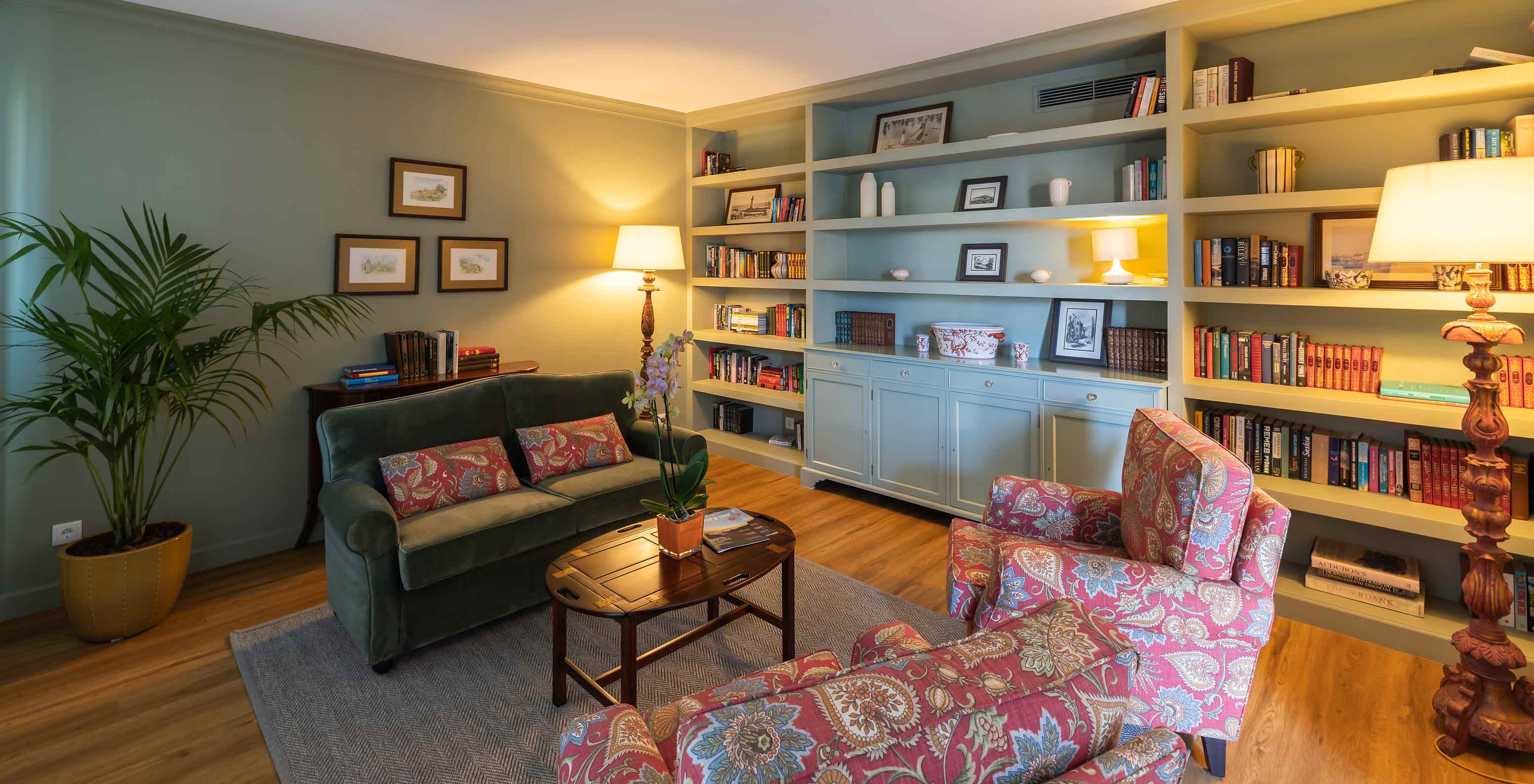 Biblioteca del Pestana Quinta Perestrello con un sofá, una estantería, una planta y una lámpara de pie