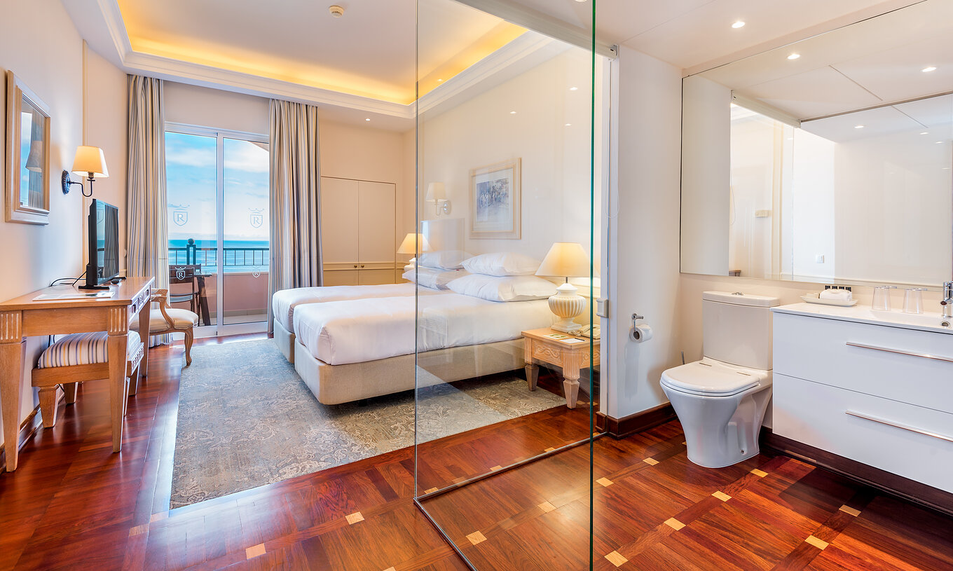 El cuarto Deluxe con Balcón del Pestana Royal All Inclusive cuenta con dos camas individuales, mesa de noche y televisión