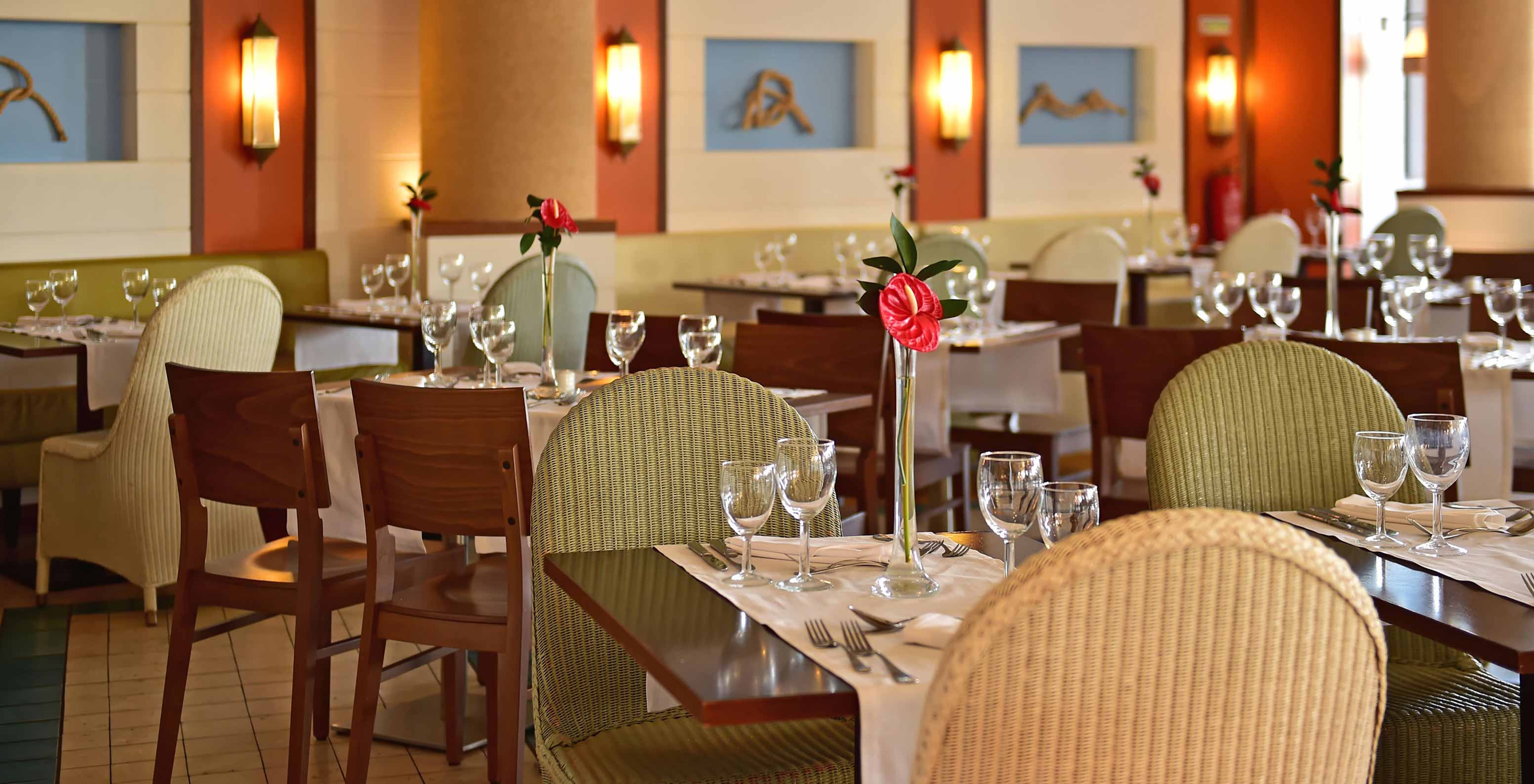 Restaurante Marés, Resort 5 estrellas en Porto Santo tiene un espacio con sillas verdes y mesas de madera