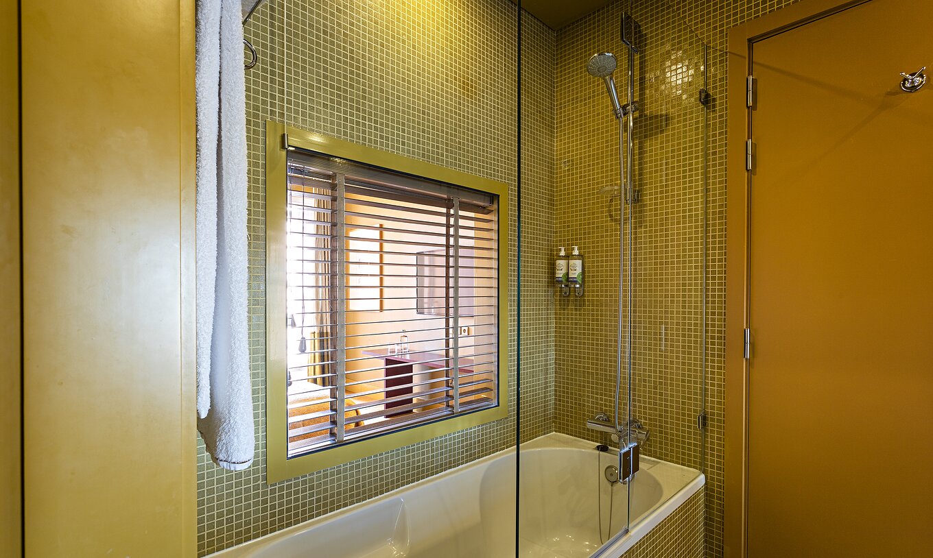 La Suite Balcony tiene un baño con bañera y ventana al dormitorio